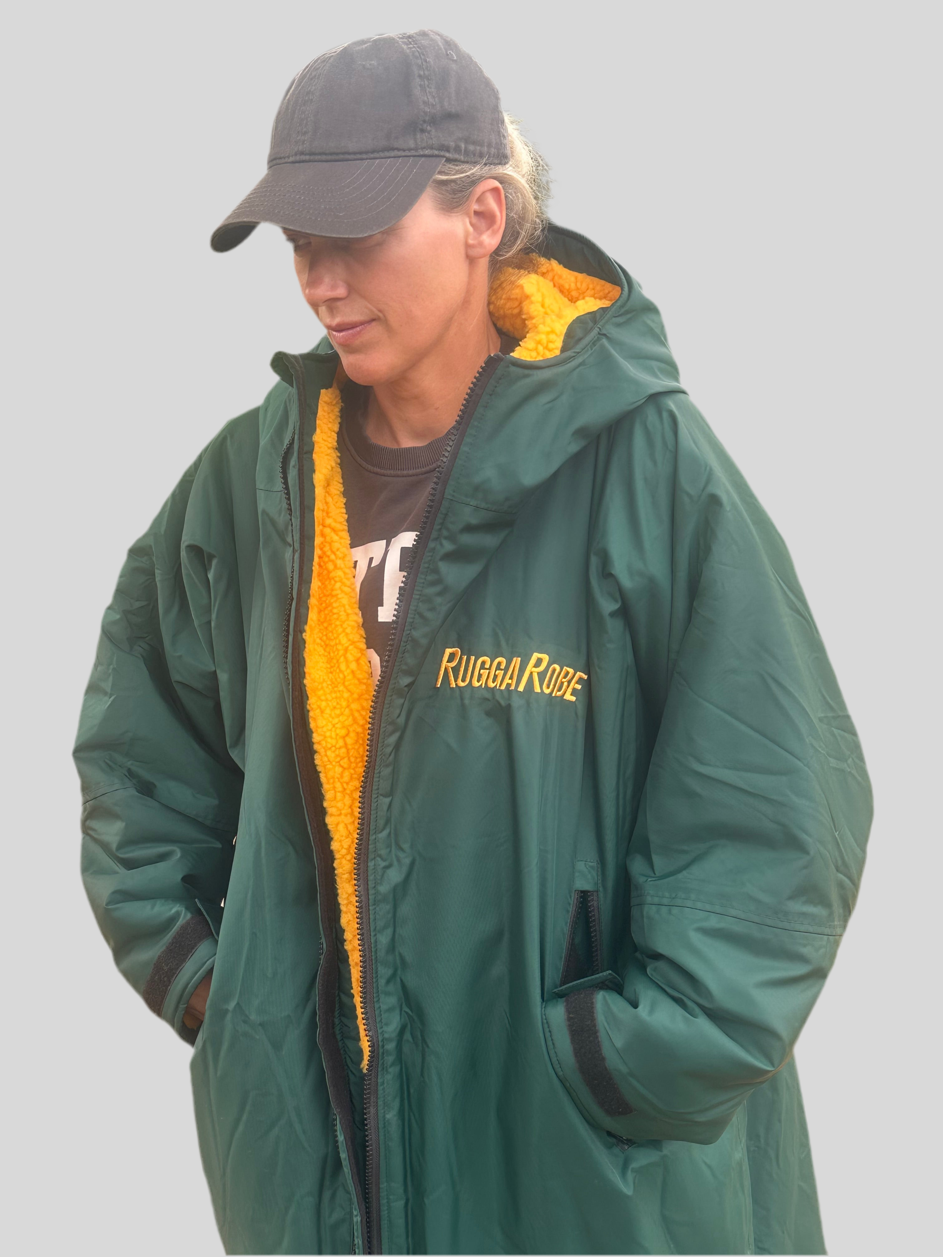 Person wearing a greenruggarobe with gold fleece lining and a cap on a plain background