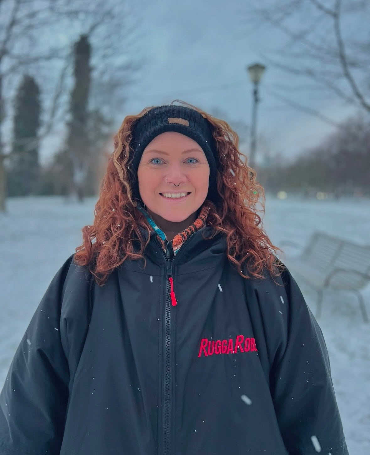 Model wearing RuggaRobe black change robe with red fleece interior in a snowey park