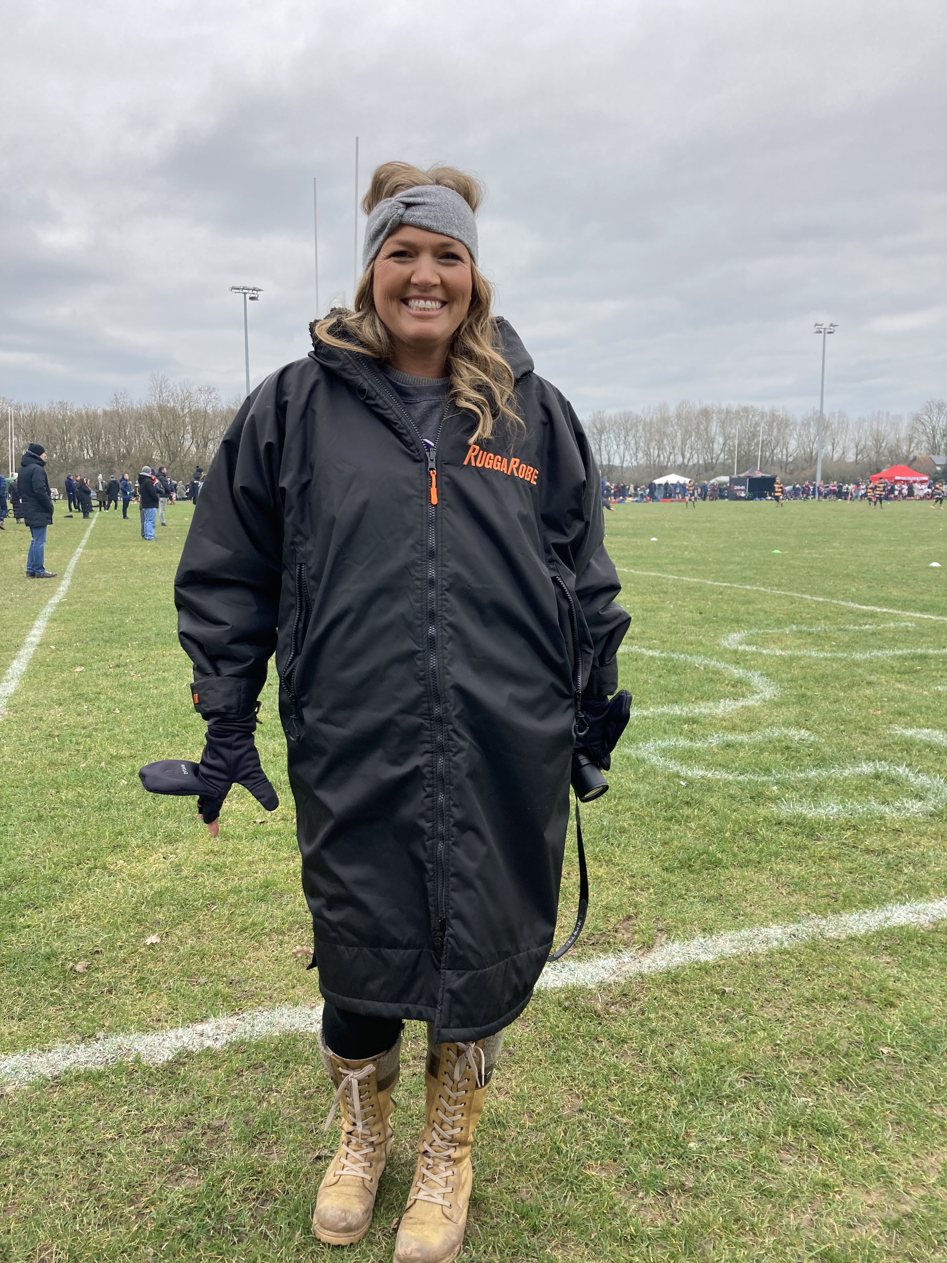 A person wearing a black ruggarobe change robe with black fleece, standing on an outdoor field.