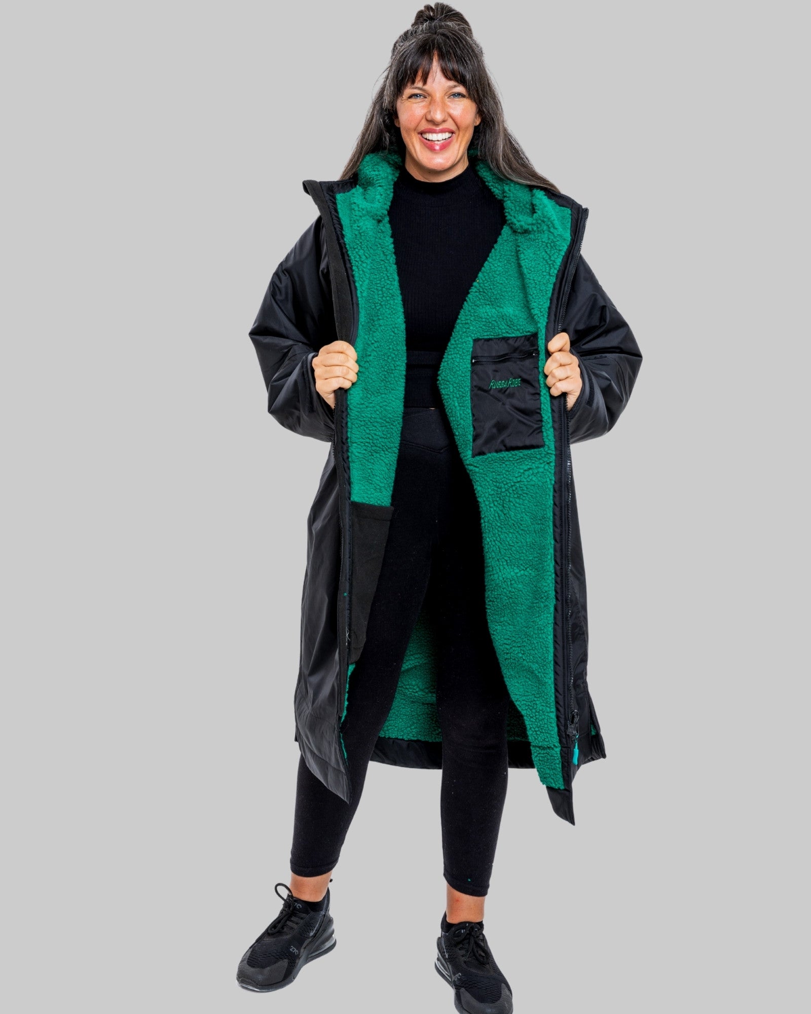 Person wearing a black changerobe with green lining on a gray background