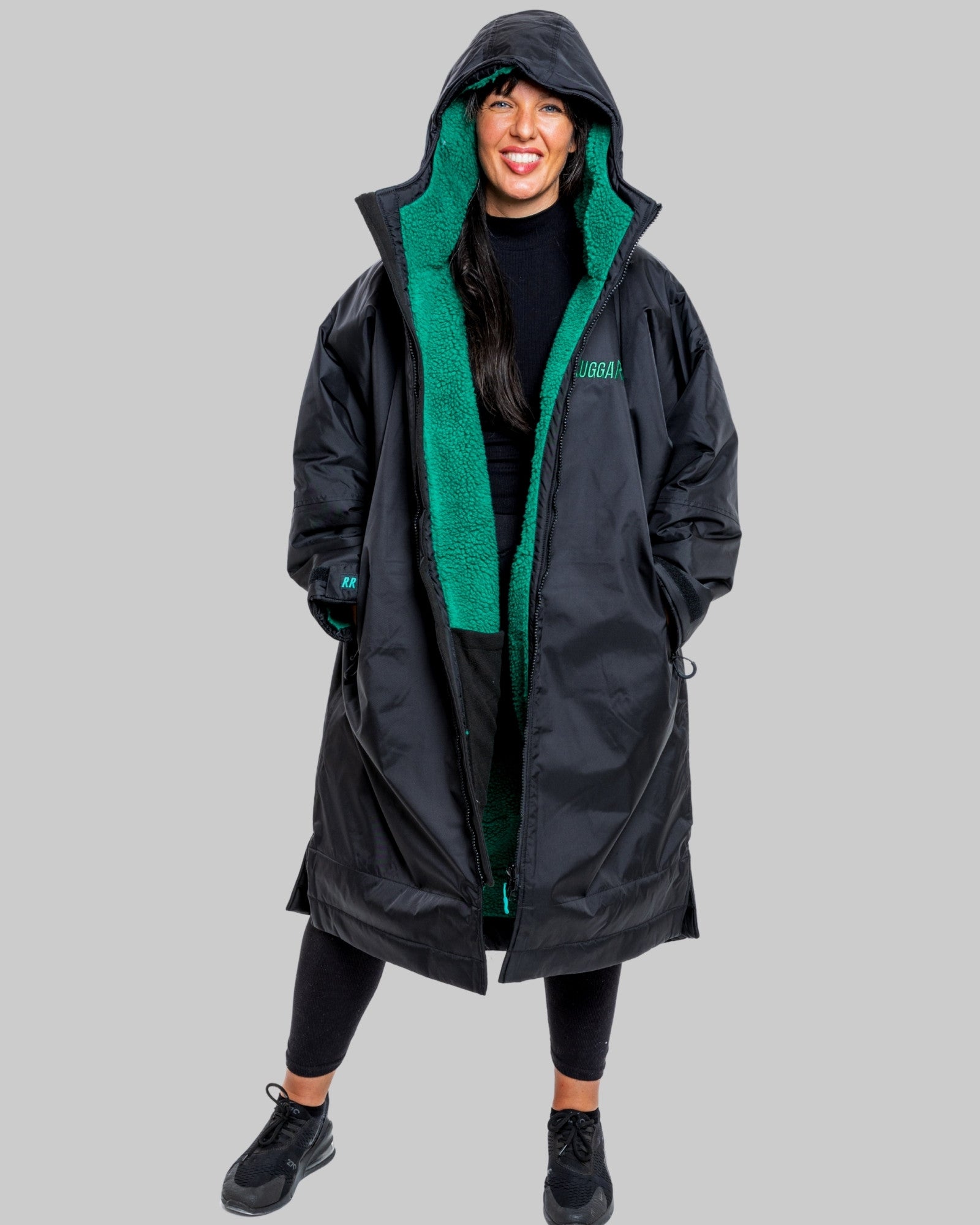 Person wearing a black ruggarobe with green lining on a gray background