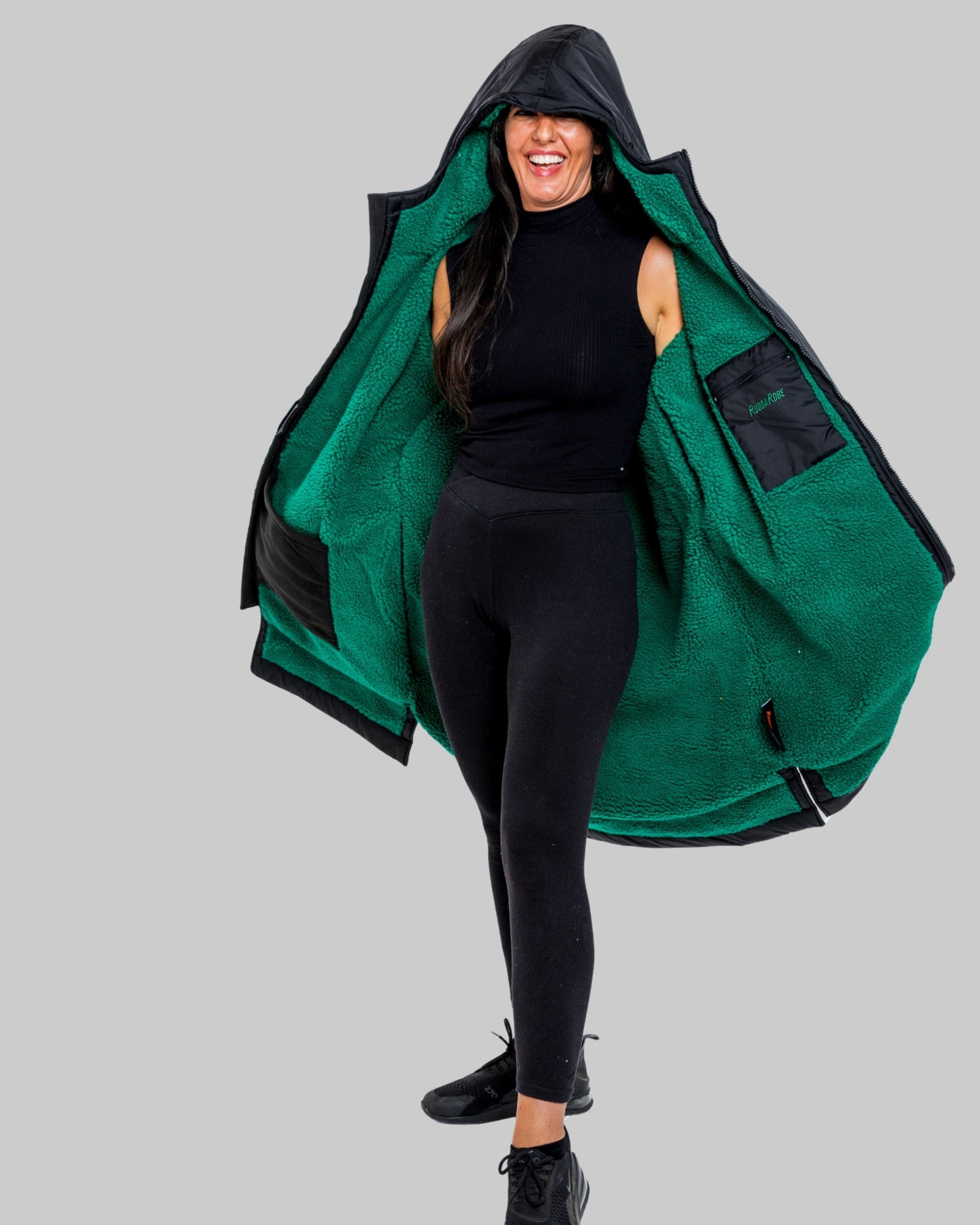 Person wearing a black changerobe with green lining on a gray background