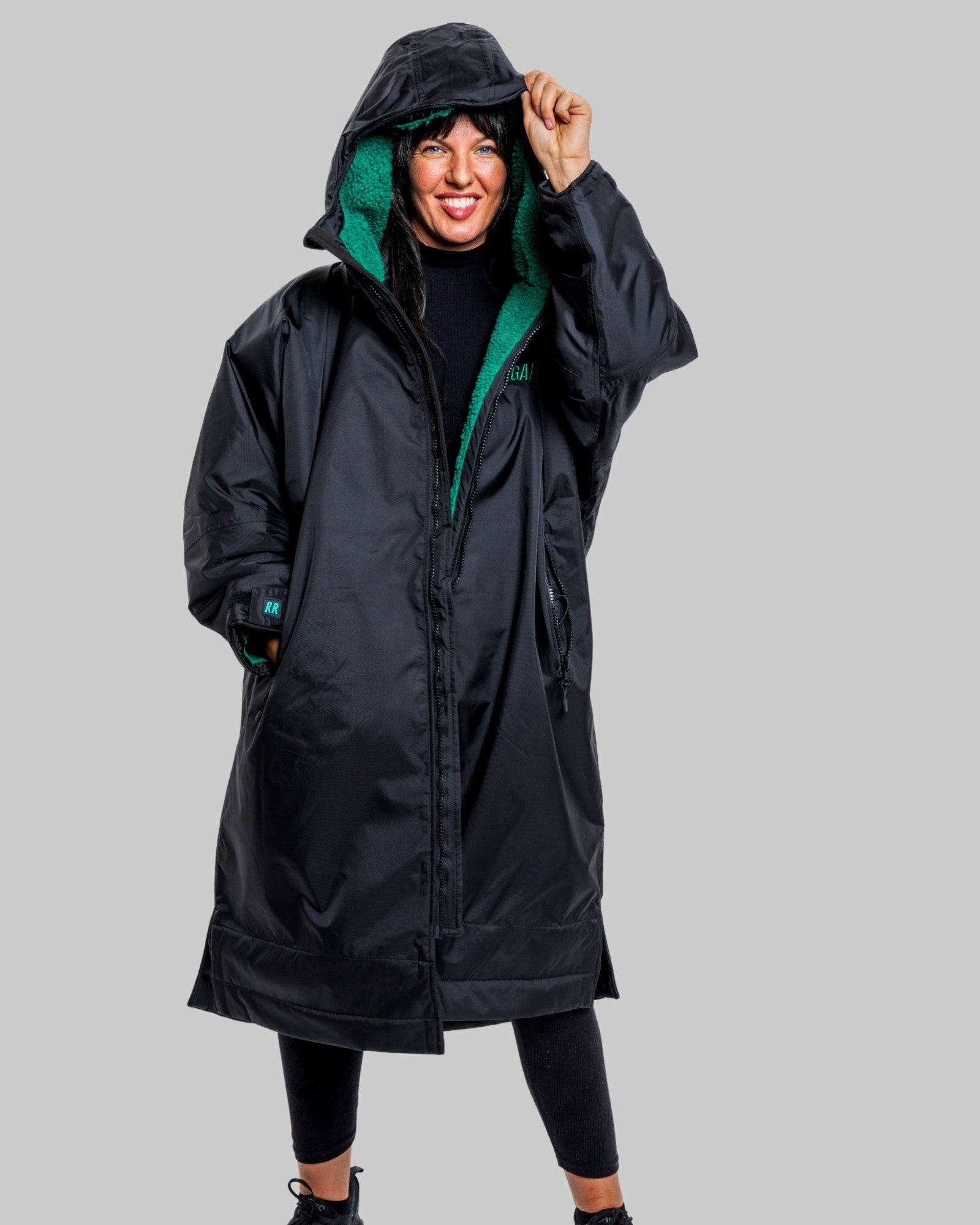 Person wearing a black changerobe with green lining on a gray background