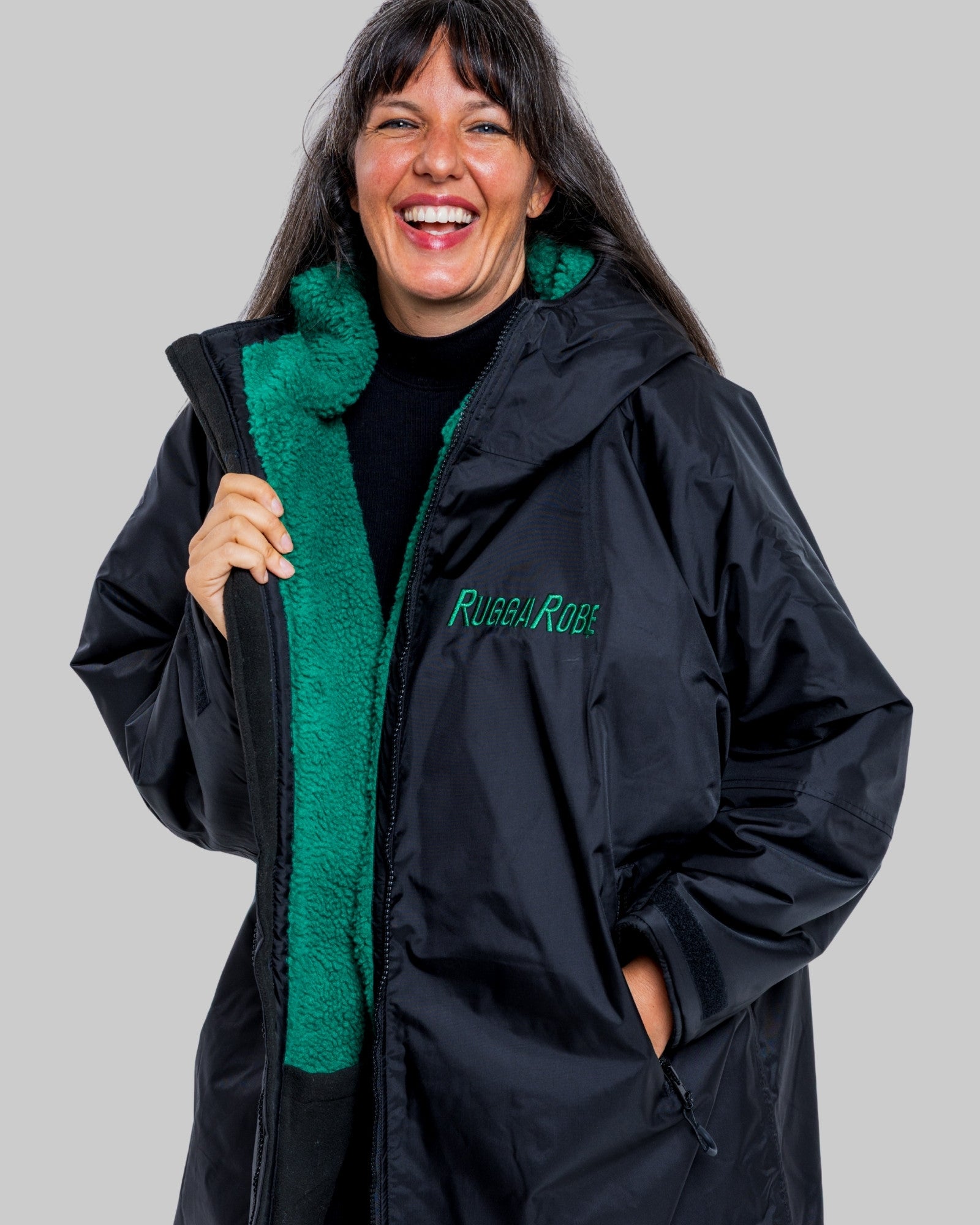 Person wearing a black jacket with green lining and 'Rubba Robe' branding on a grey background