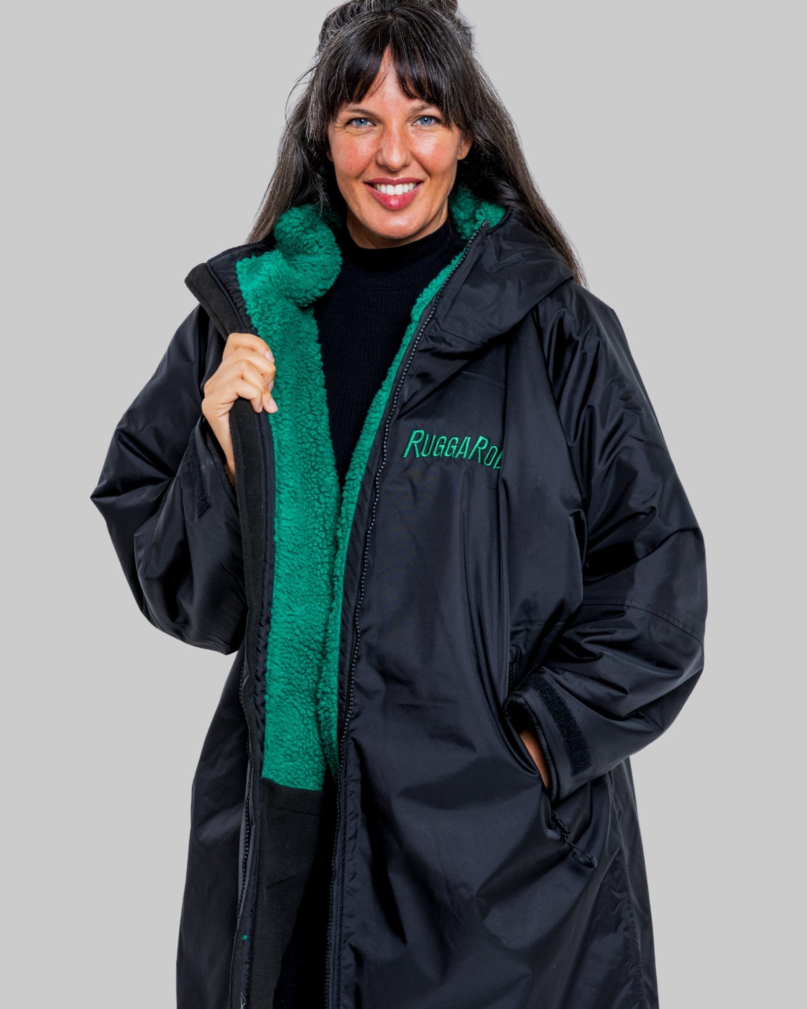 Woman wearing a black coat with green lining and 'Ruggarobe' branding on a gray background