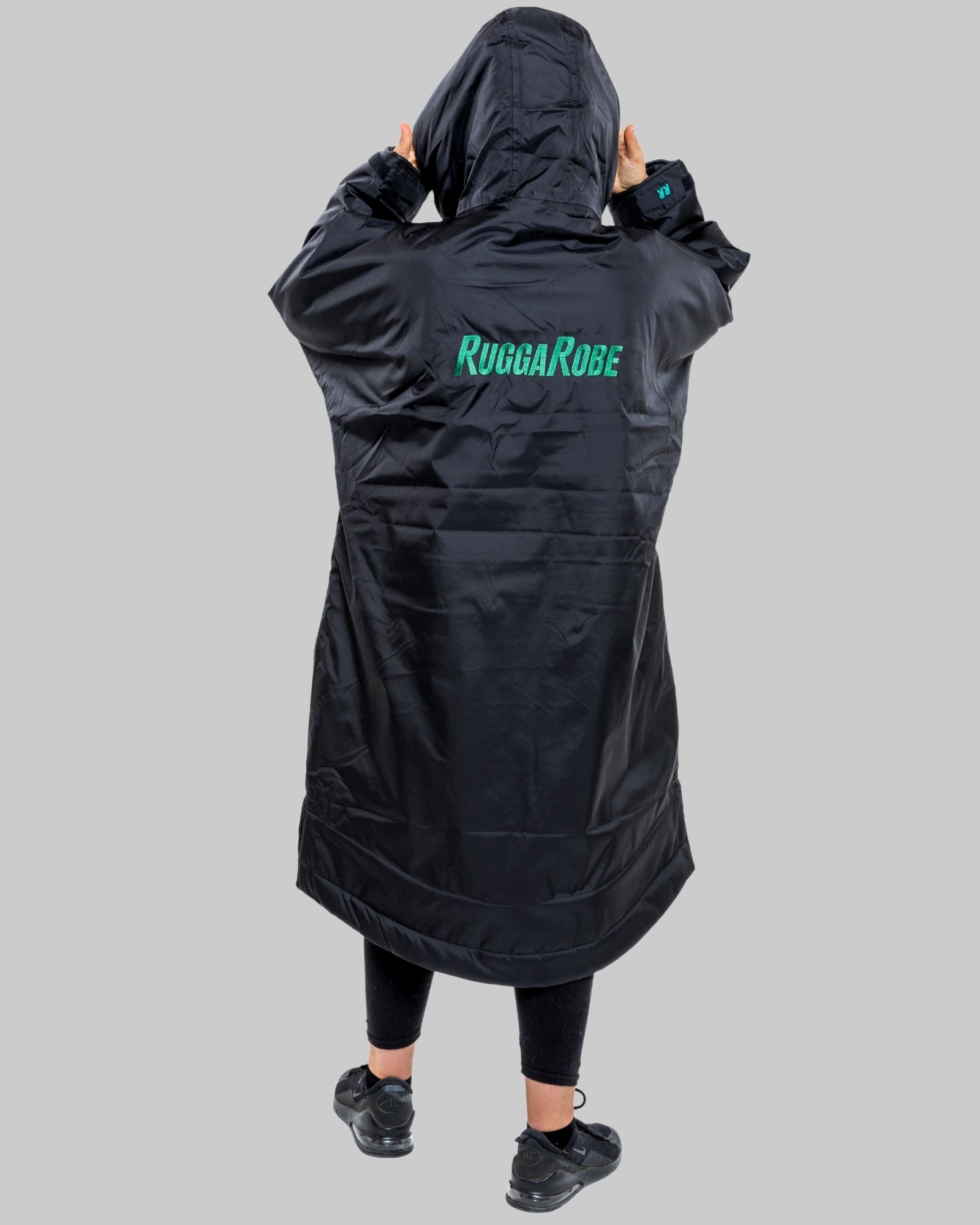 Person wearing a black hooded garment with 'Rugbarobe' branding on the back against a gray background