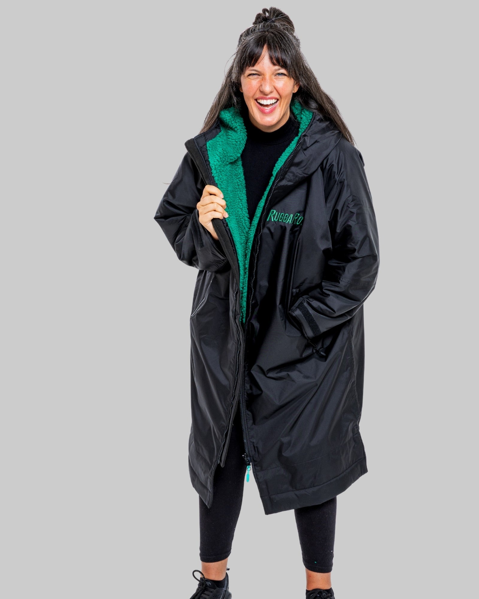 Person wearing a black changerobe with green lining on a gray background