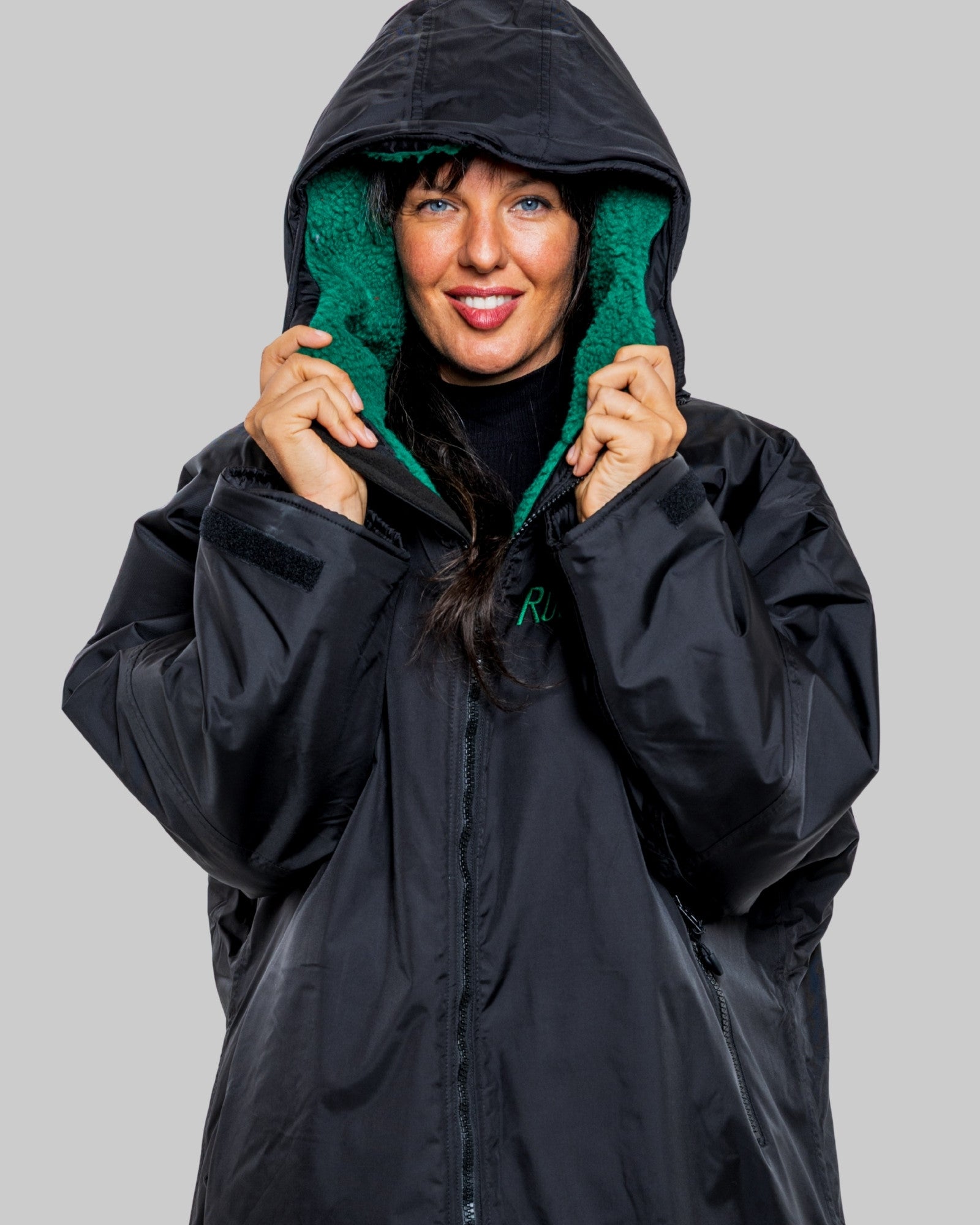 Person wearing a black changerobe with green lining on a gray background