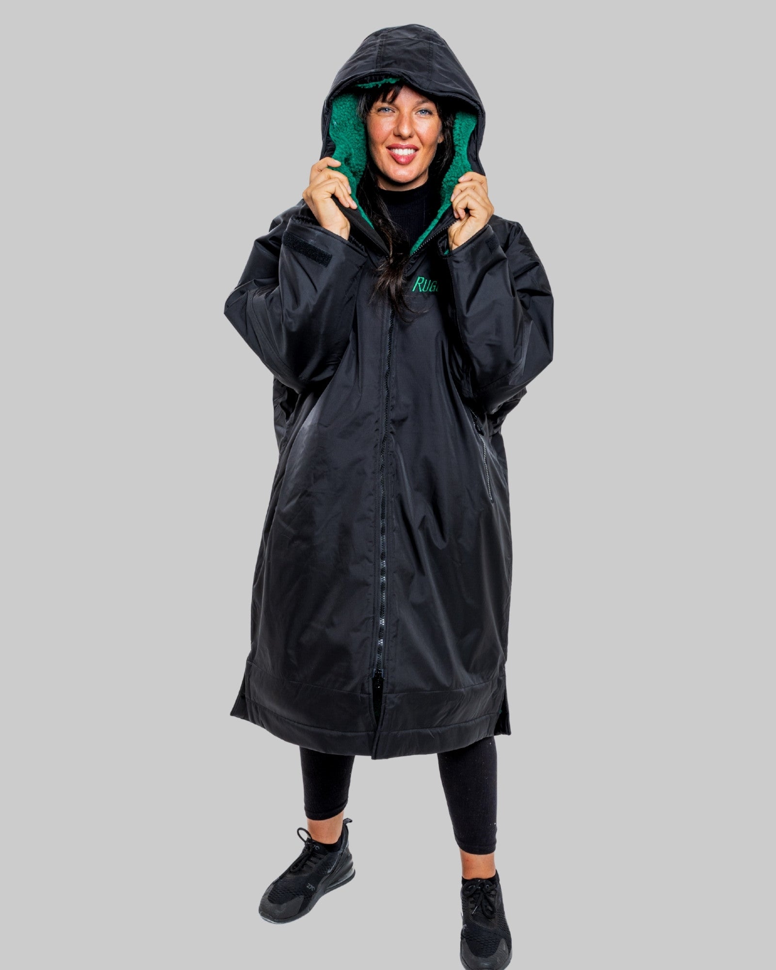 Person wearing a black changerobe with green lining on a gray background
