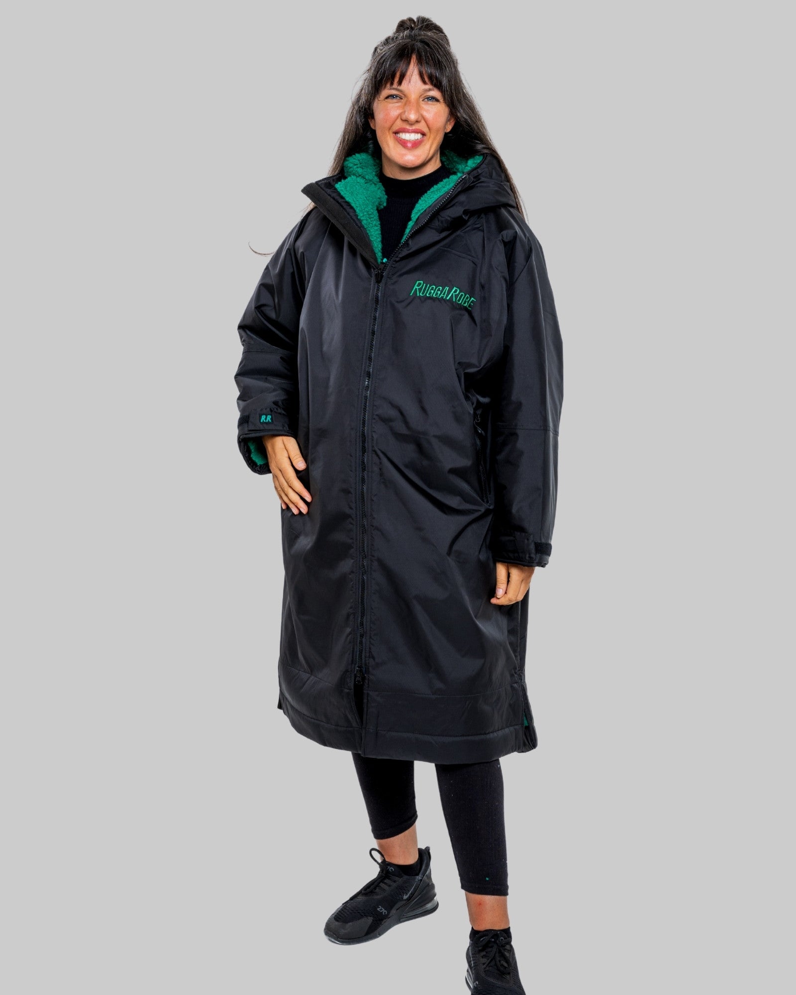 Person wearing a black changerobe with green lining on a gray background