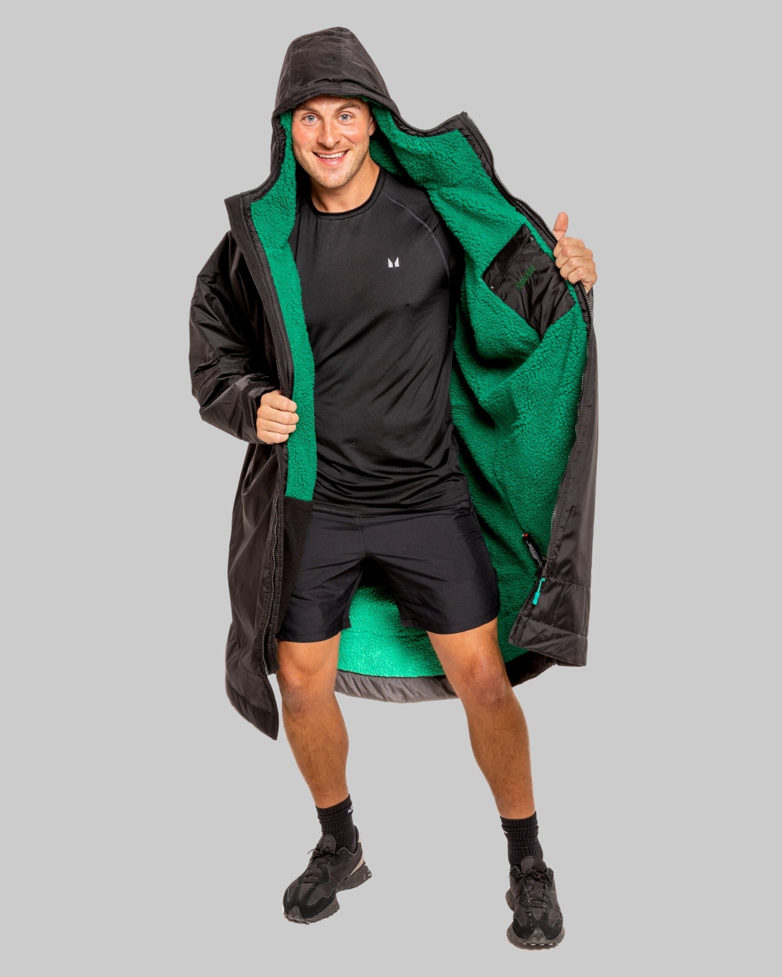 Person wearing a black changerobe with green lining on a gray background