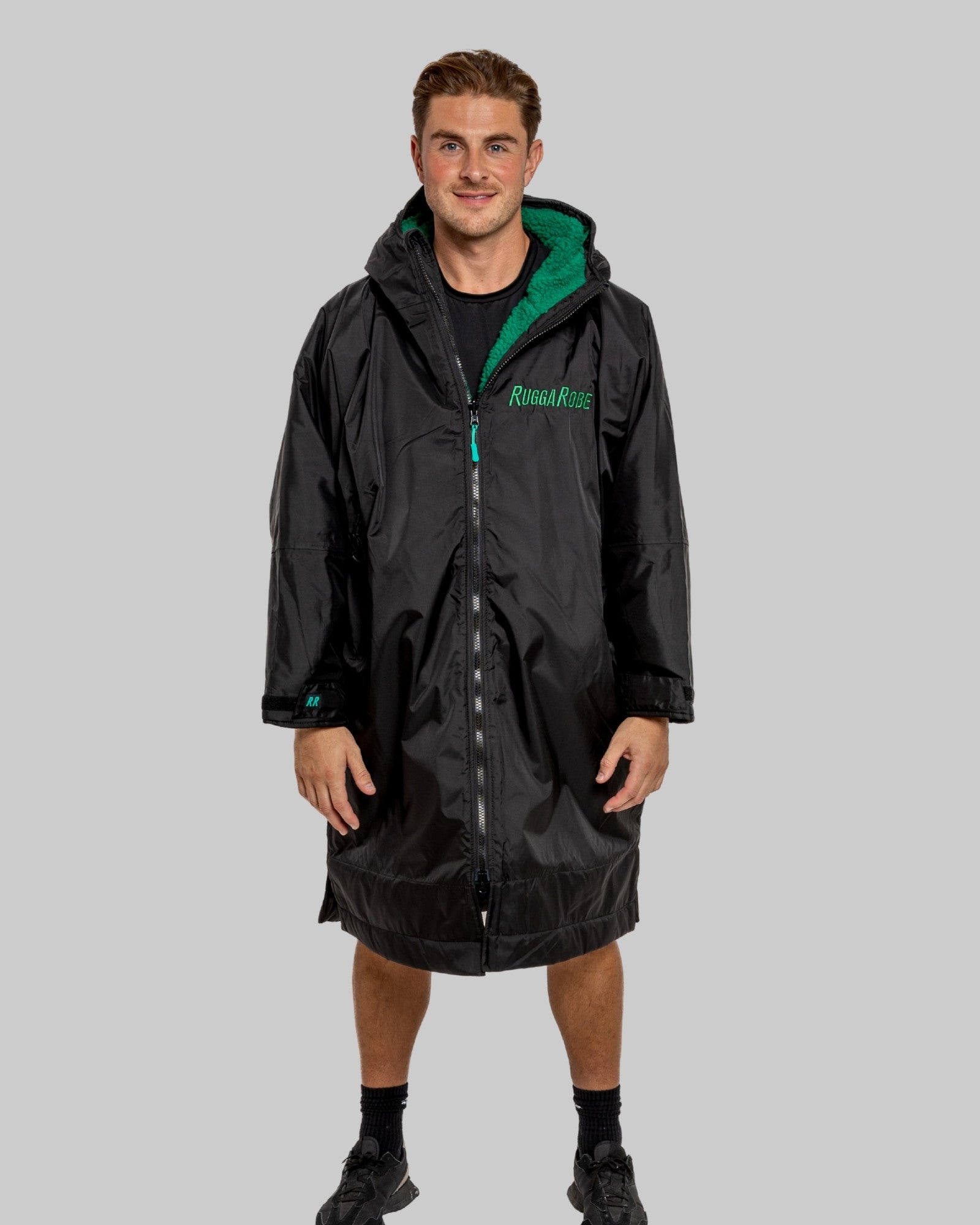 Person wearing a black changerobe with green lining on a gray background