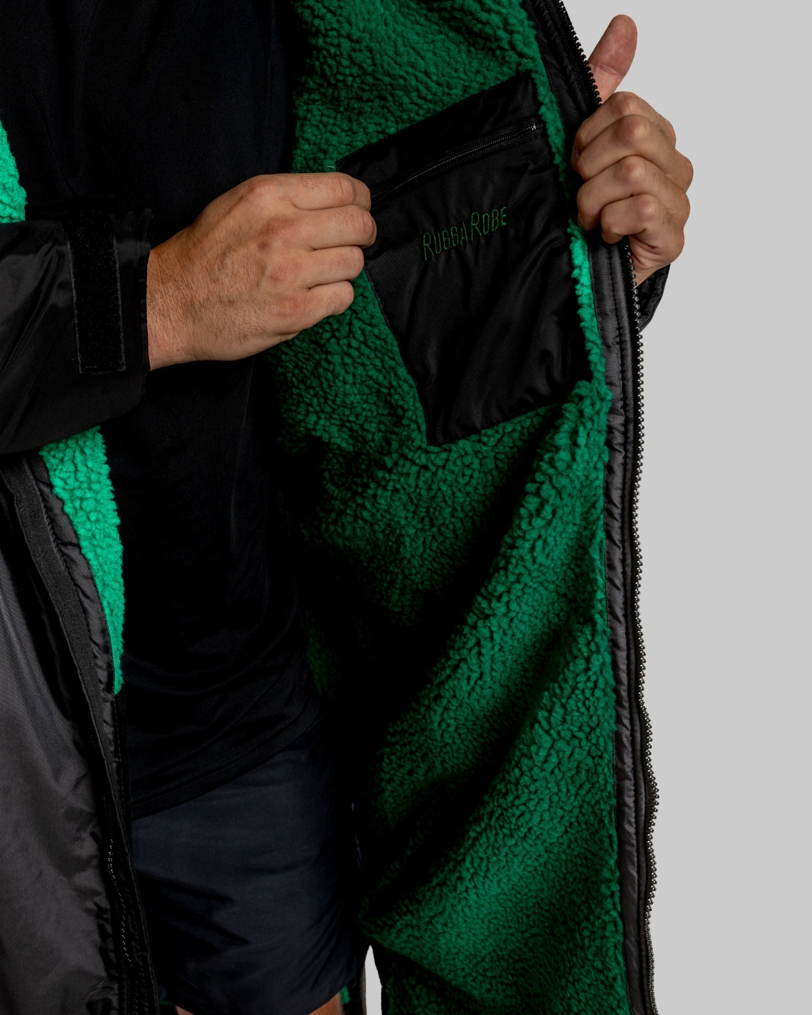 Person wearing a black changerobe with green lining on a gray background