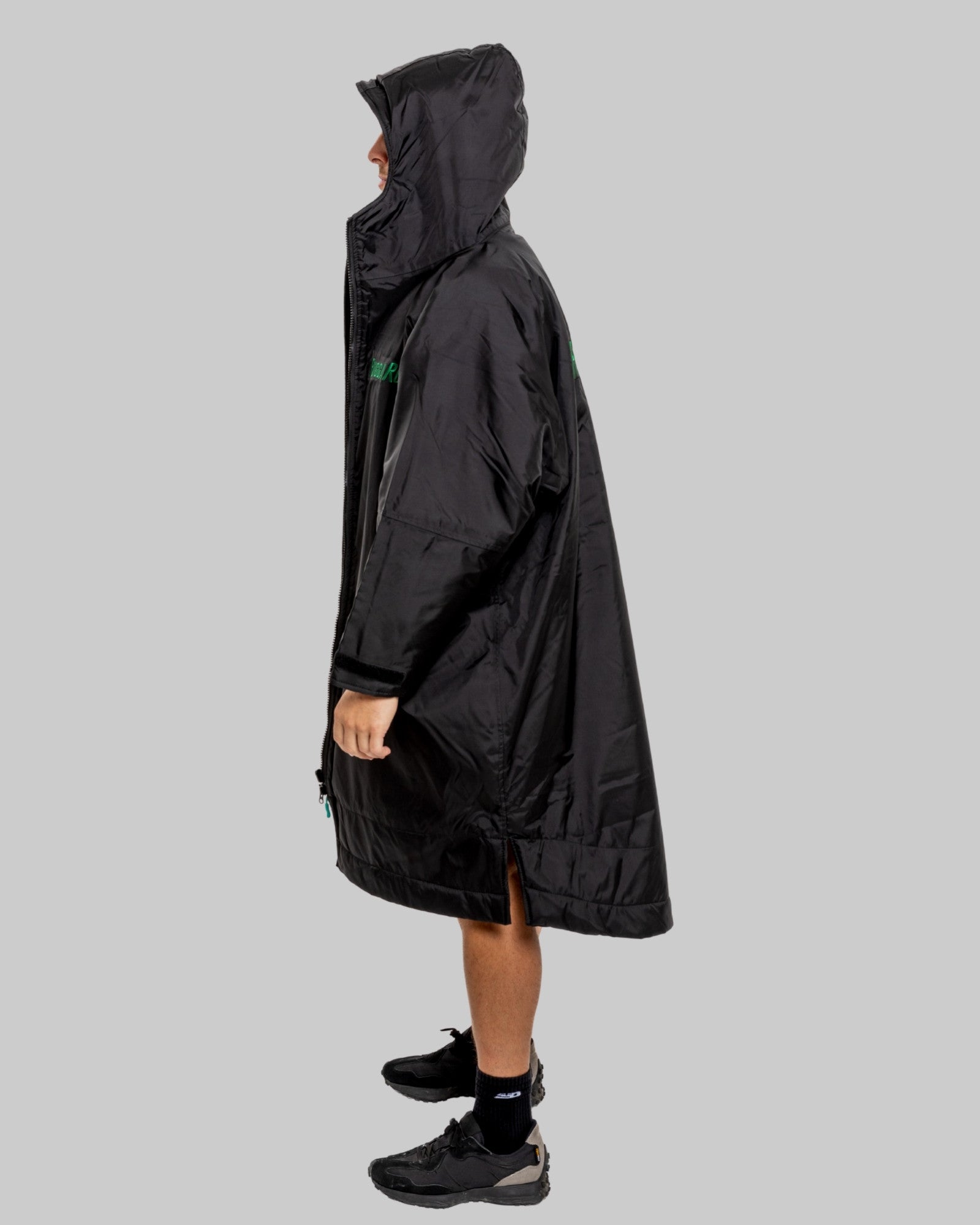 Person wearing a black changerobe with green lining on a gray background