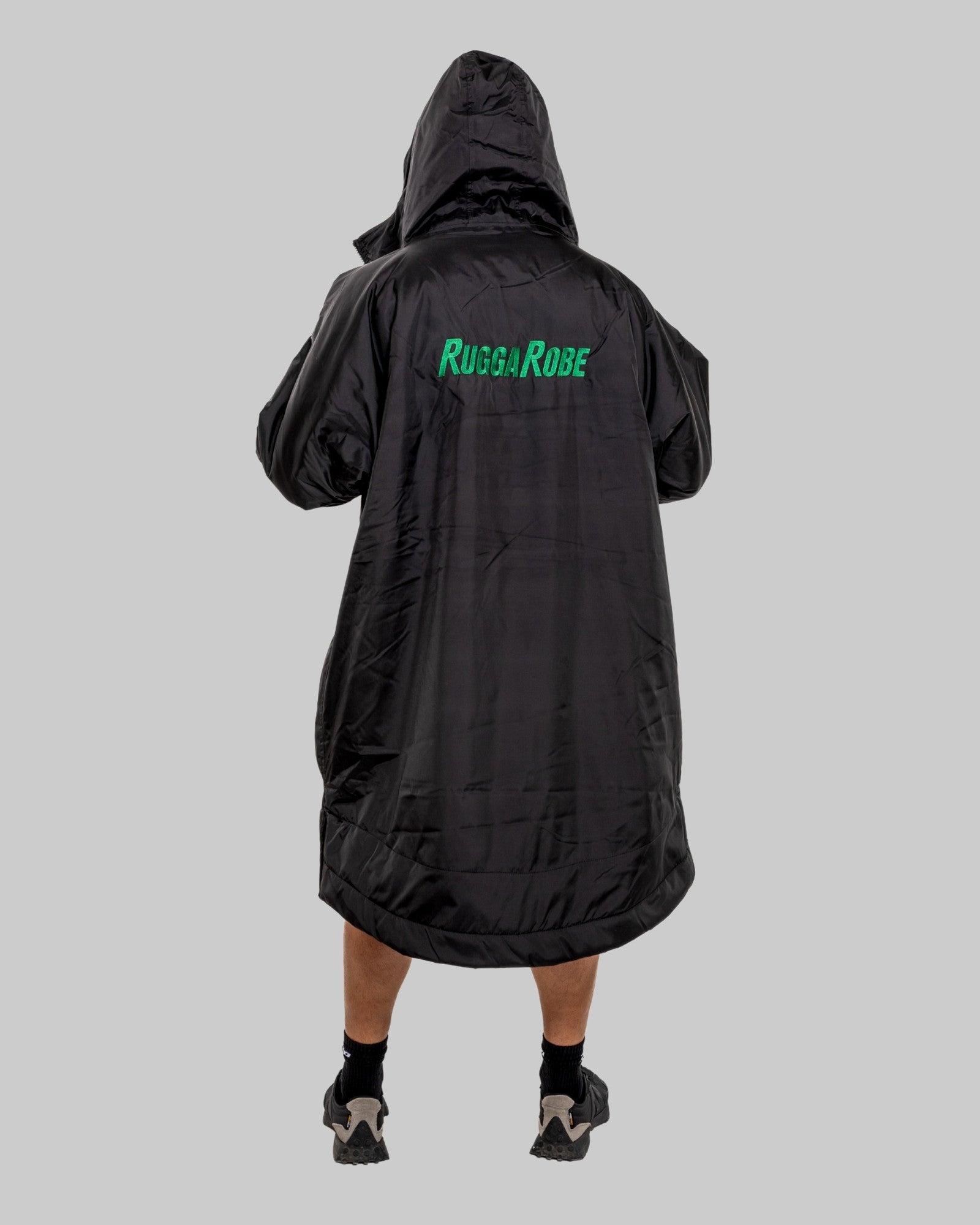 Black poncho with 'Rugga Robe' branding on the back, worn by a person against a gray background.