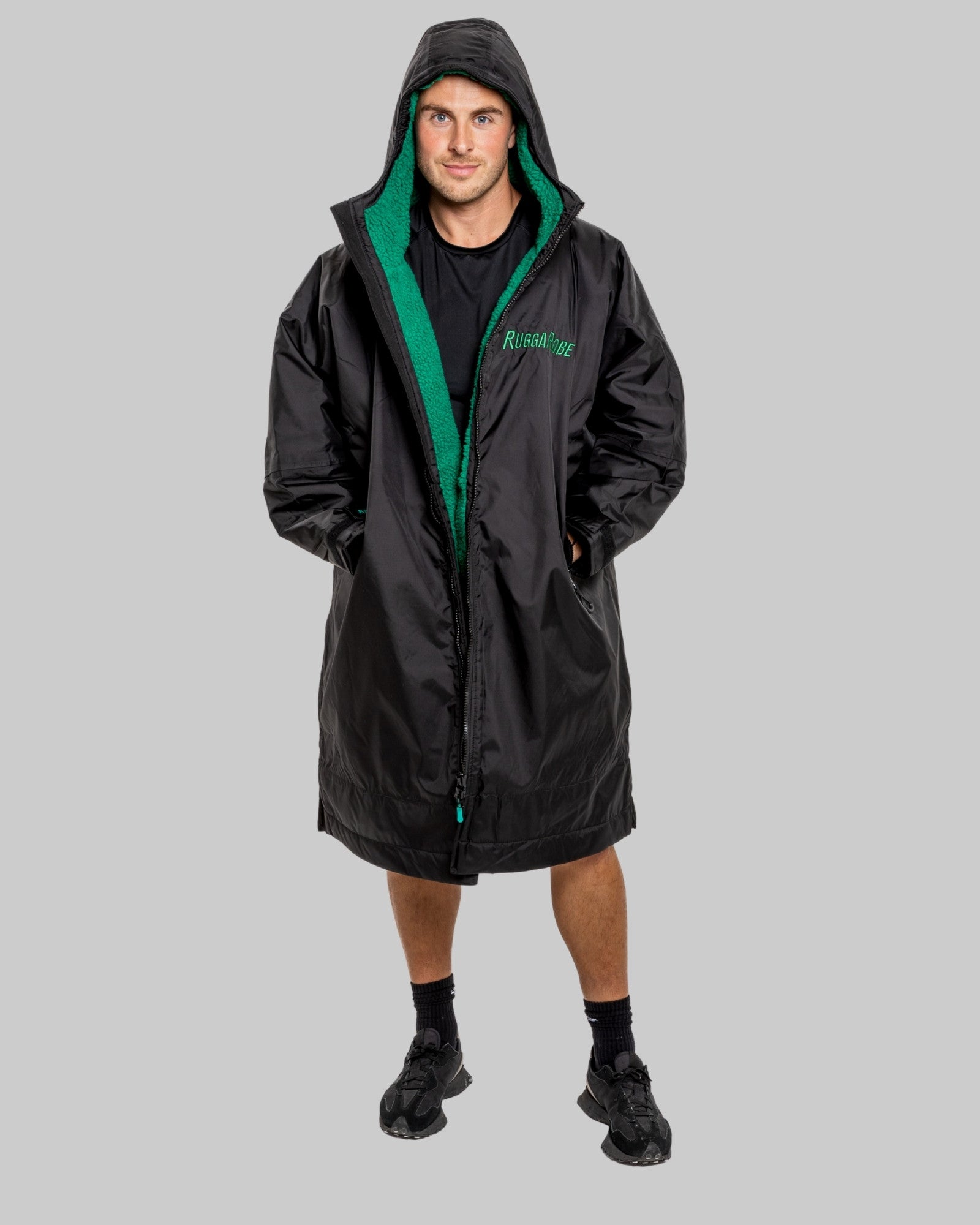 Person wearing a black changerobe with green lining on a gray background