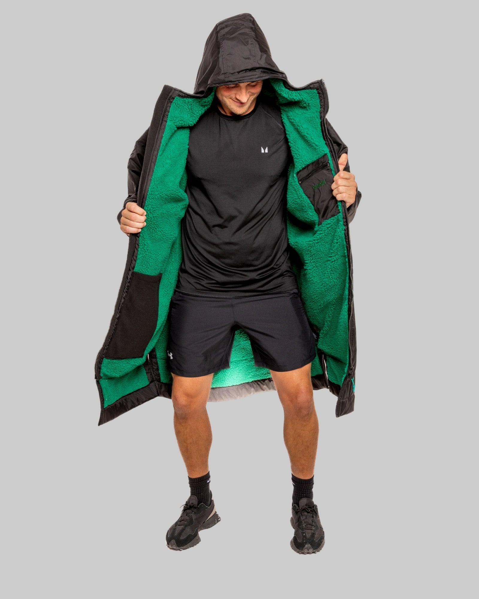 Person wearing a black changerobe with green lining on a gray background