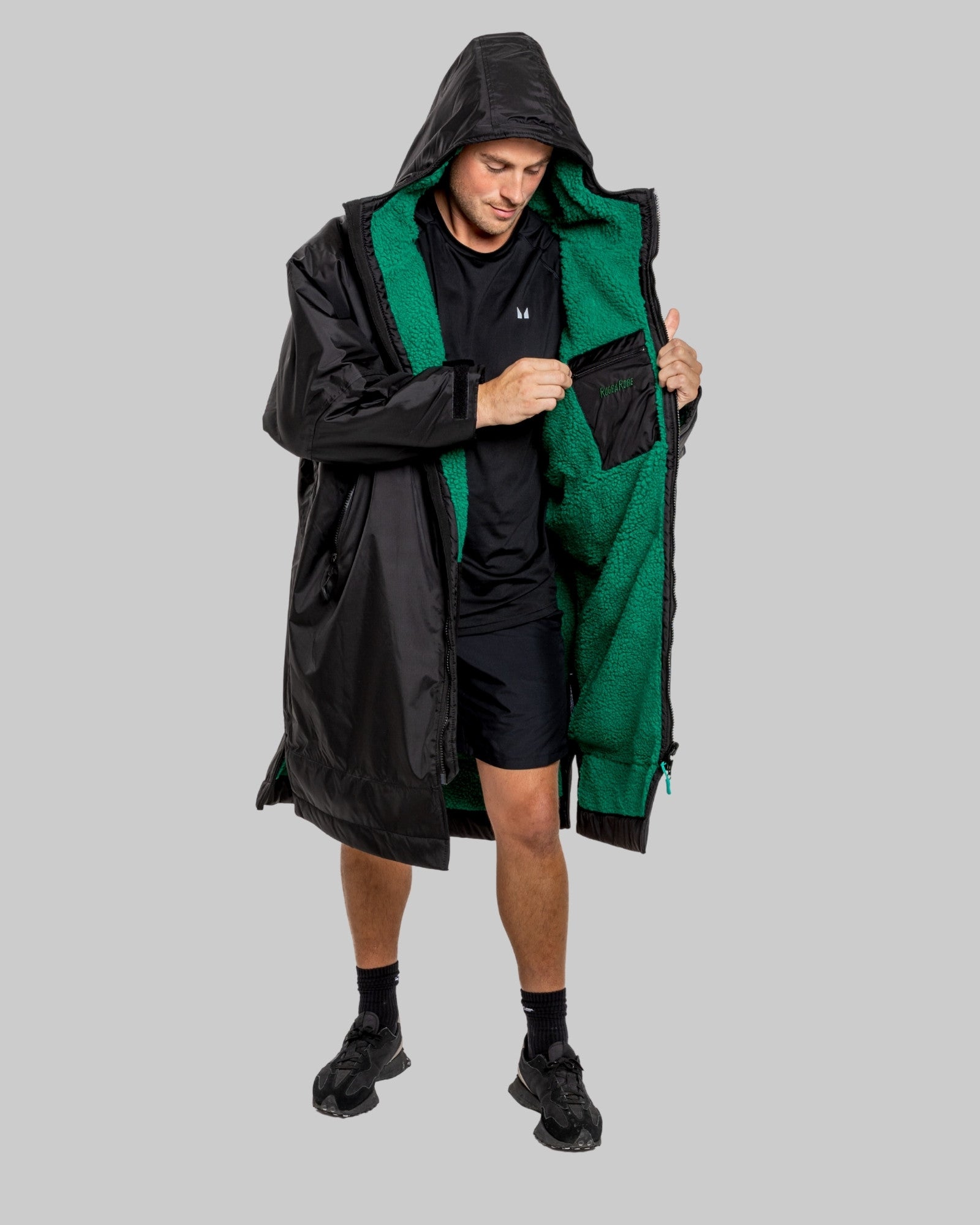 Person wearing a black changerobe with green lining on a gray background