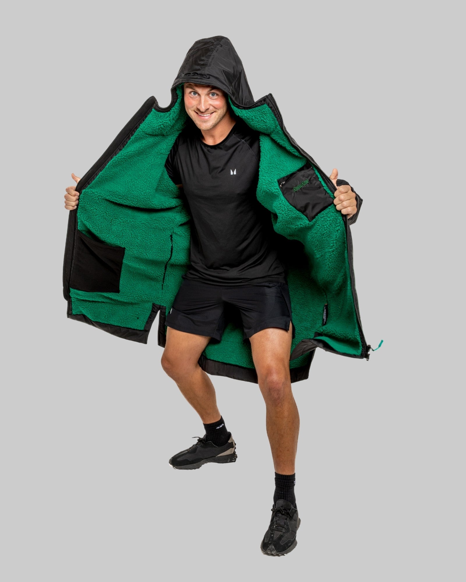 Person wearing a black changerobe with green lining on a gray background