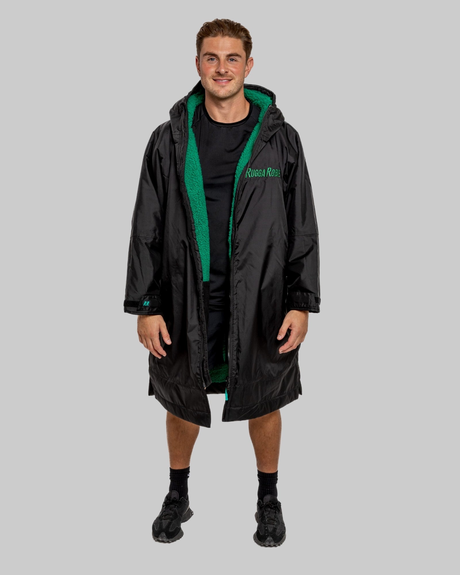 Person wearing a black changerobe with green lining on a gray background