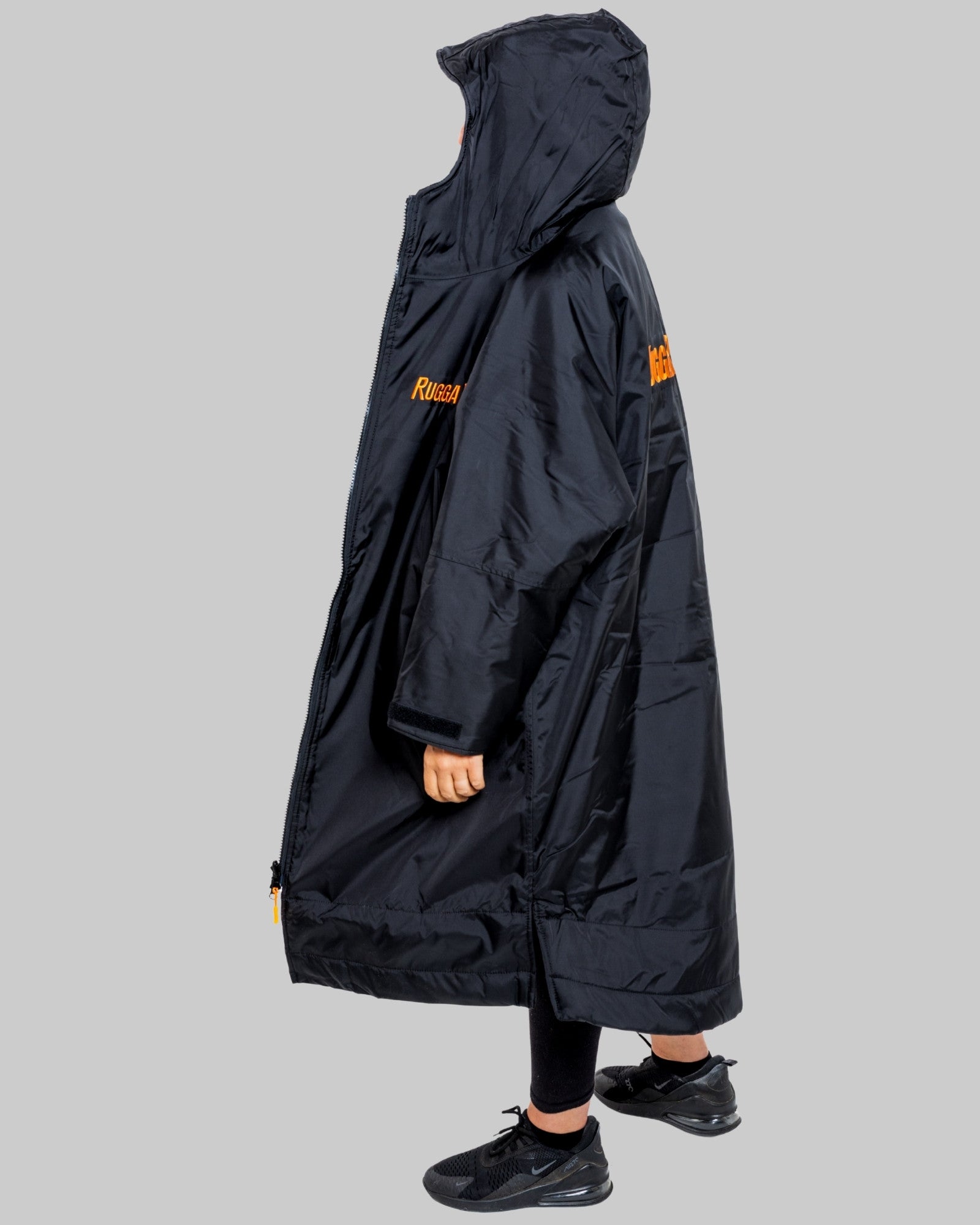 Man wearing a black changerobe with orange lining and 'RuggaRobe' branding on a grey background