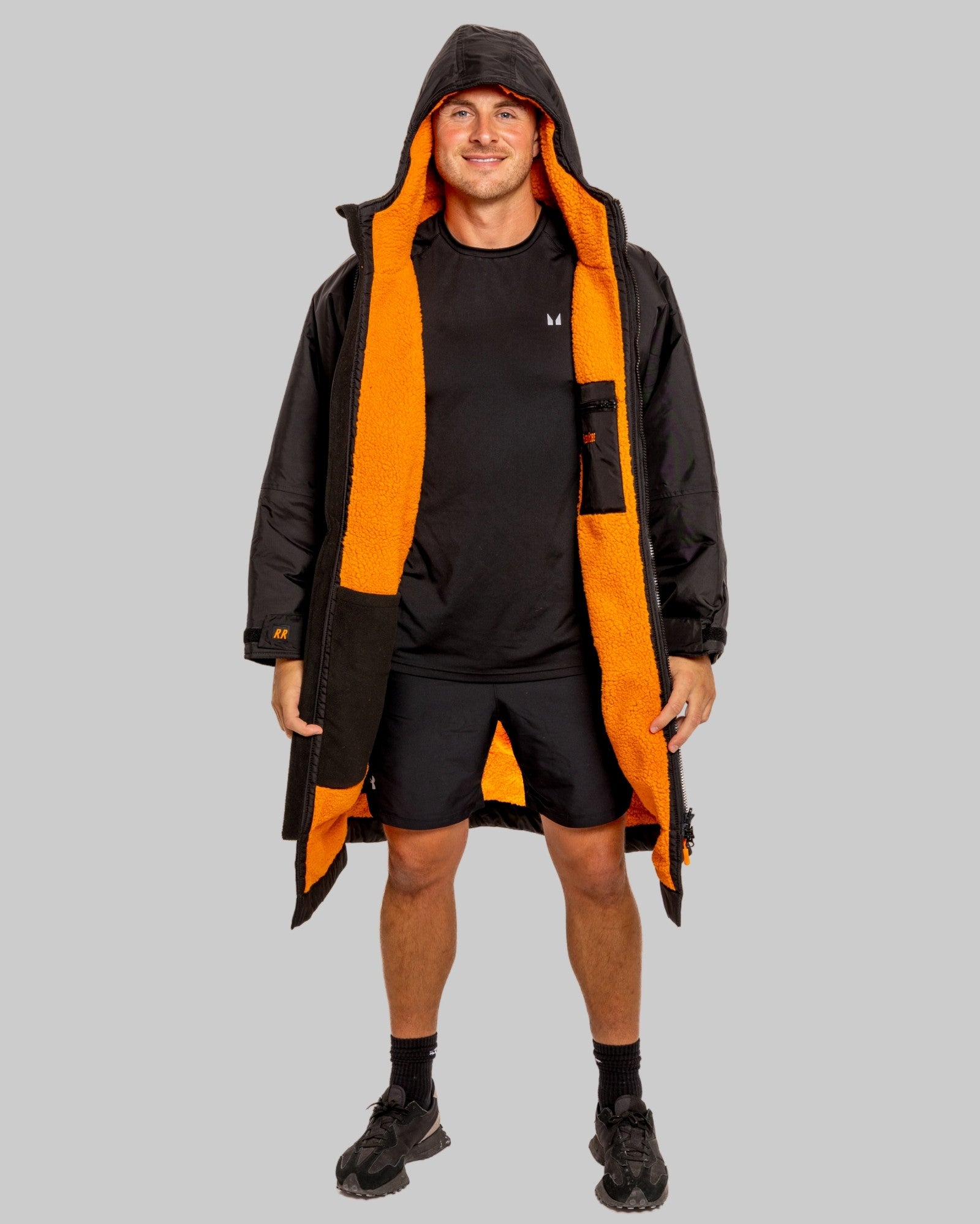 Man wearing a black changerobe with orange lining and 'RuggaRobe' branding on a grey background