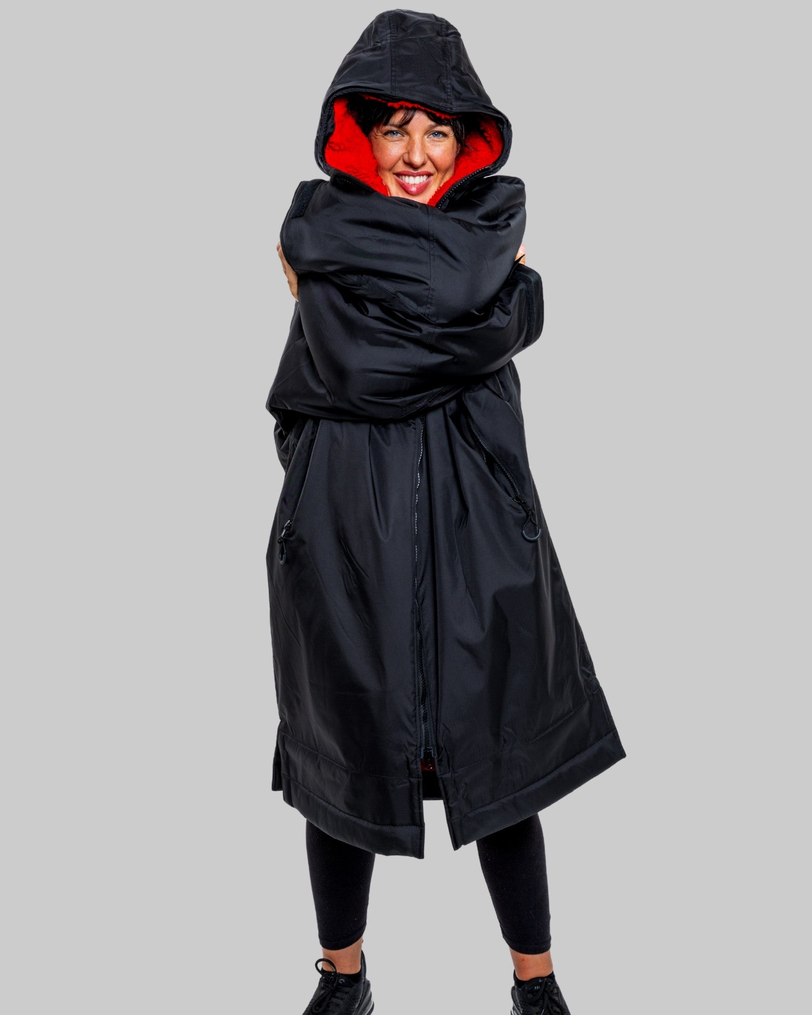 Person wearing a black hooded changerobe on a gray background