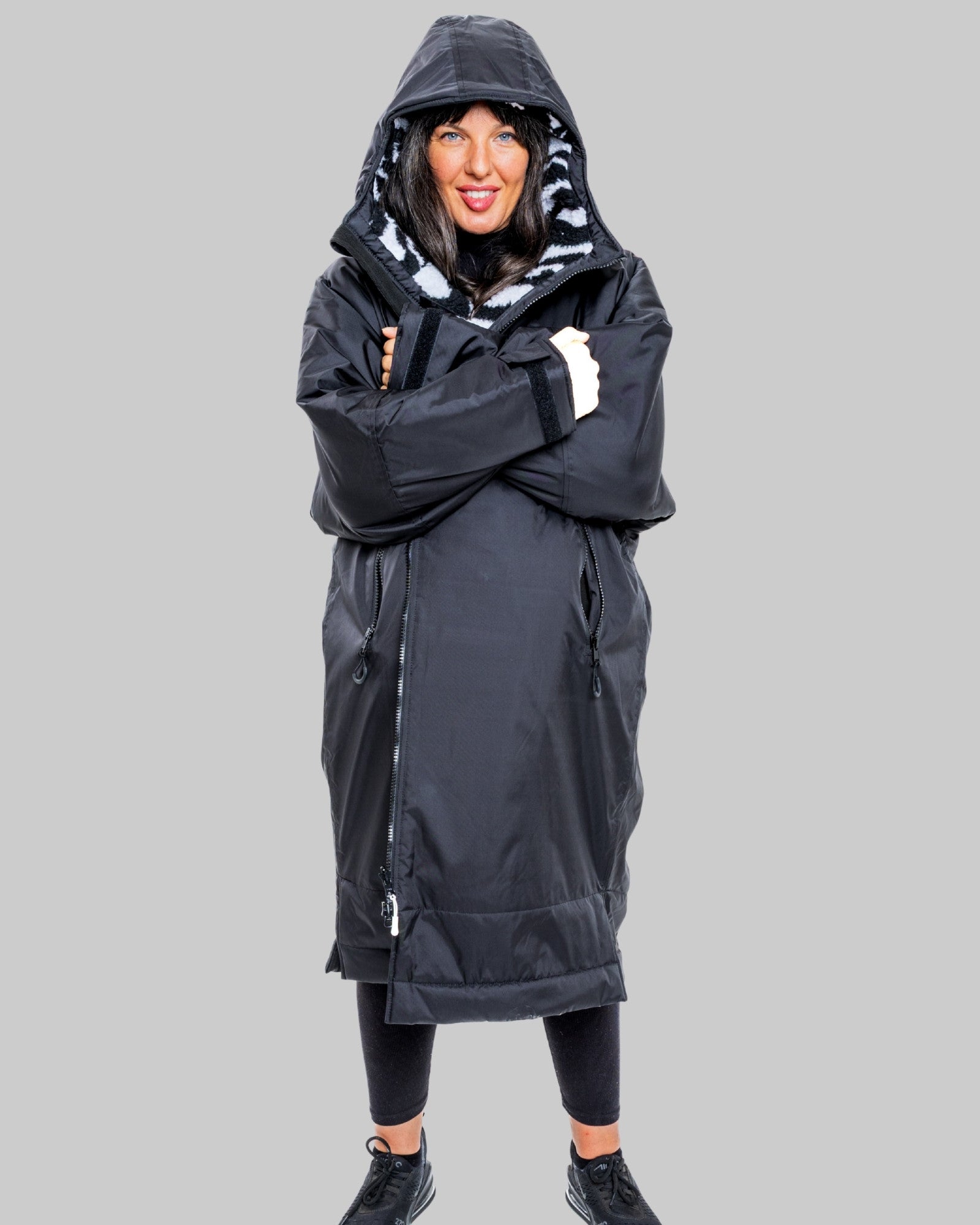 Person wearing a black with zebra patterned interior ruggarobe with on a gray background