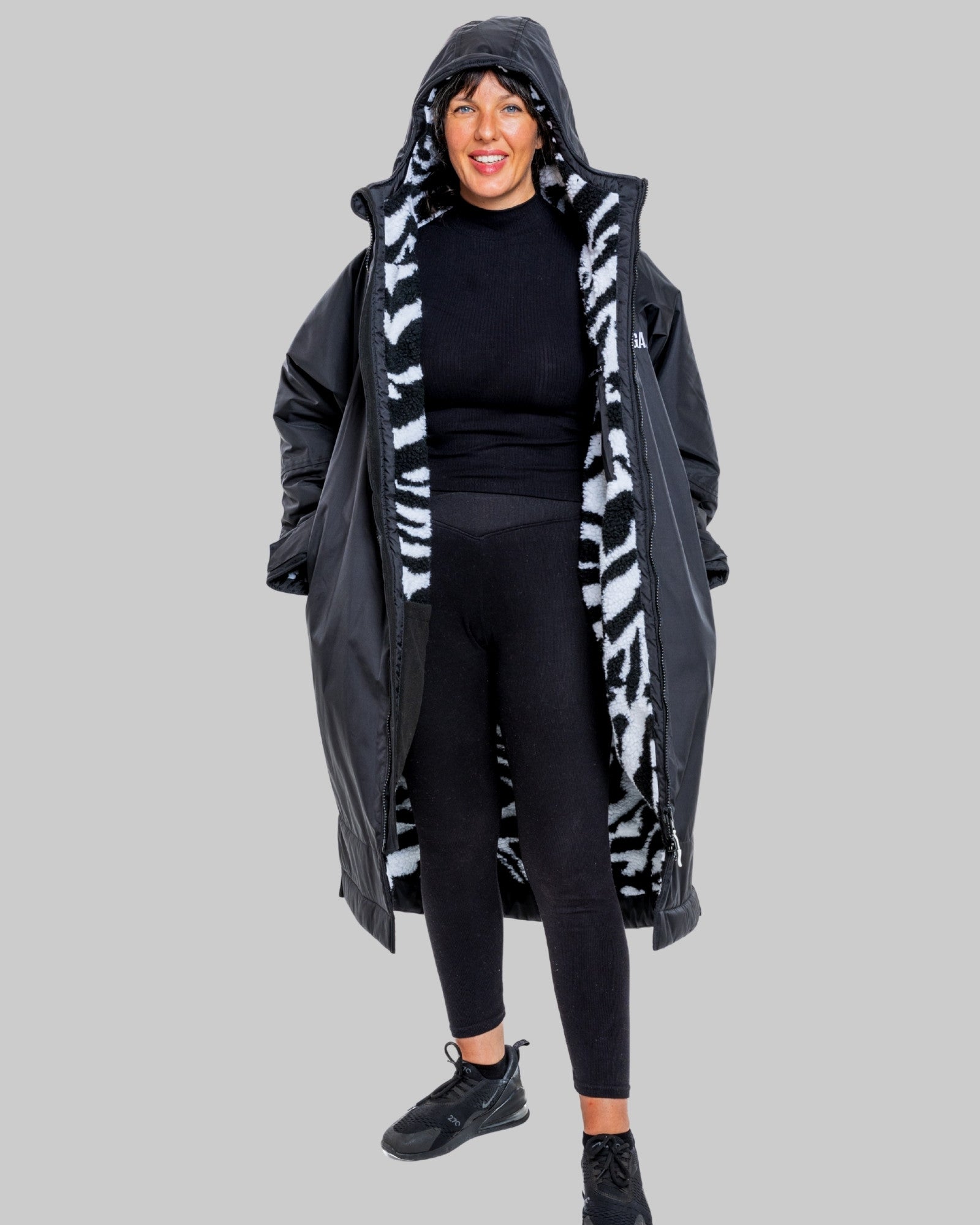 Person wearing a black with zebra patterned interior ruggarobe with on a gray background