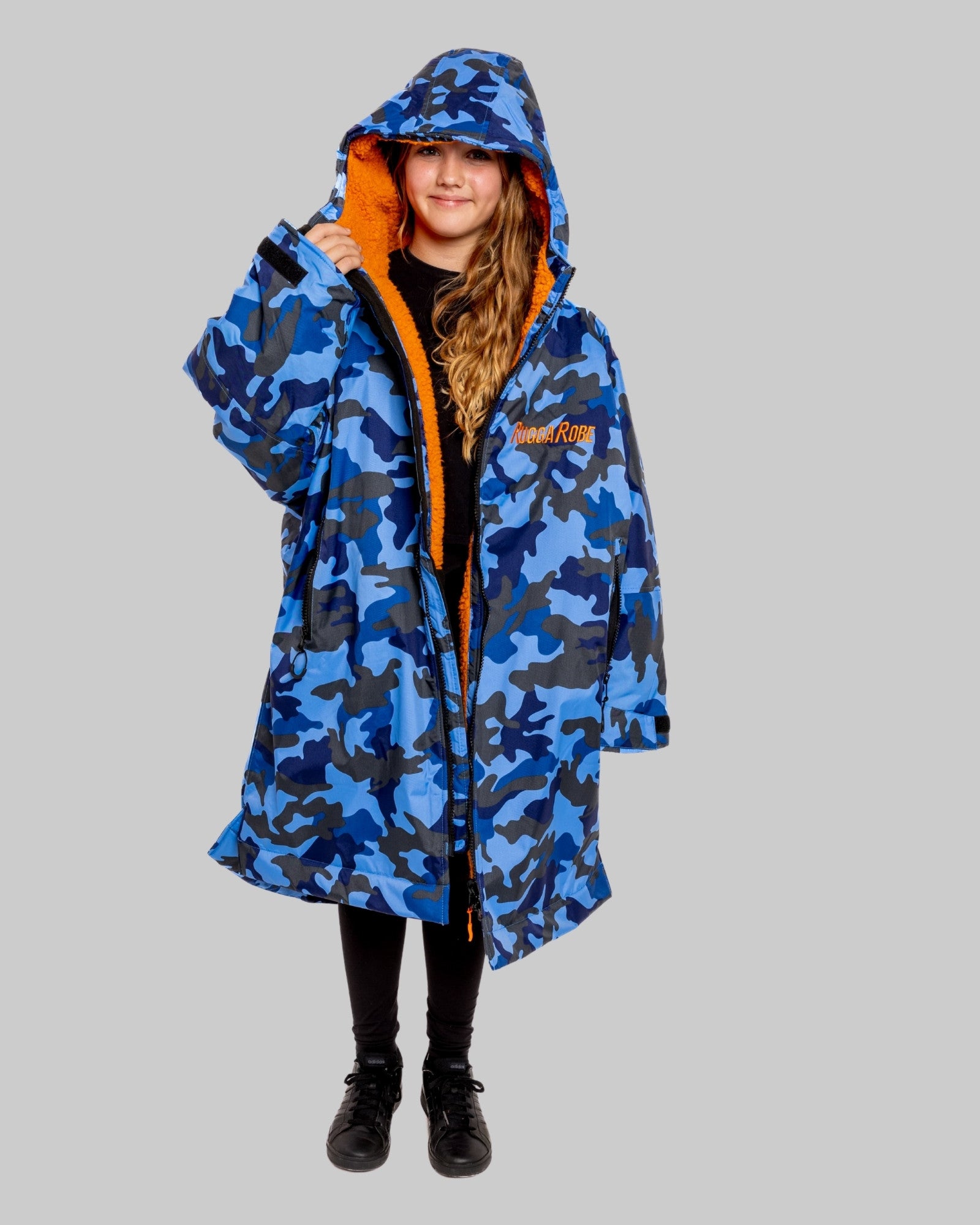 Model wearing RuggaRobe blue camo change robe with orange fleece interior on grey background