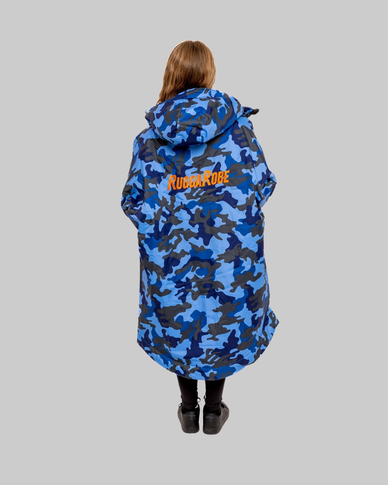 Model wearing RuggaRobe blue camo change robe with orange fleece interior on grey background