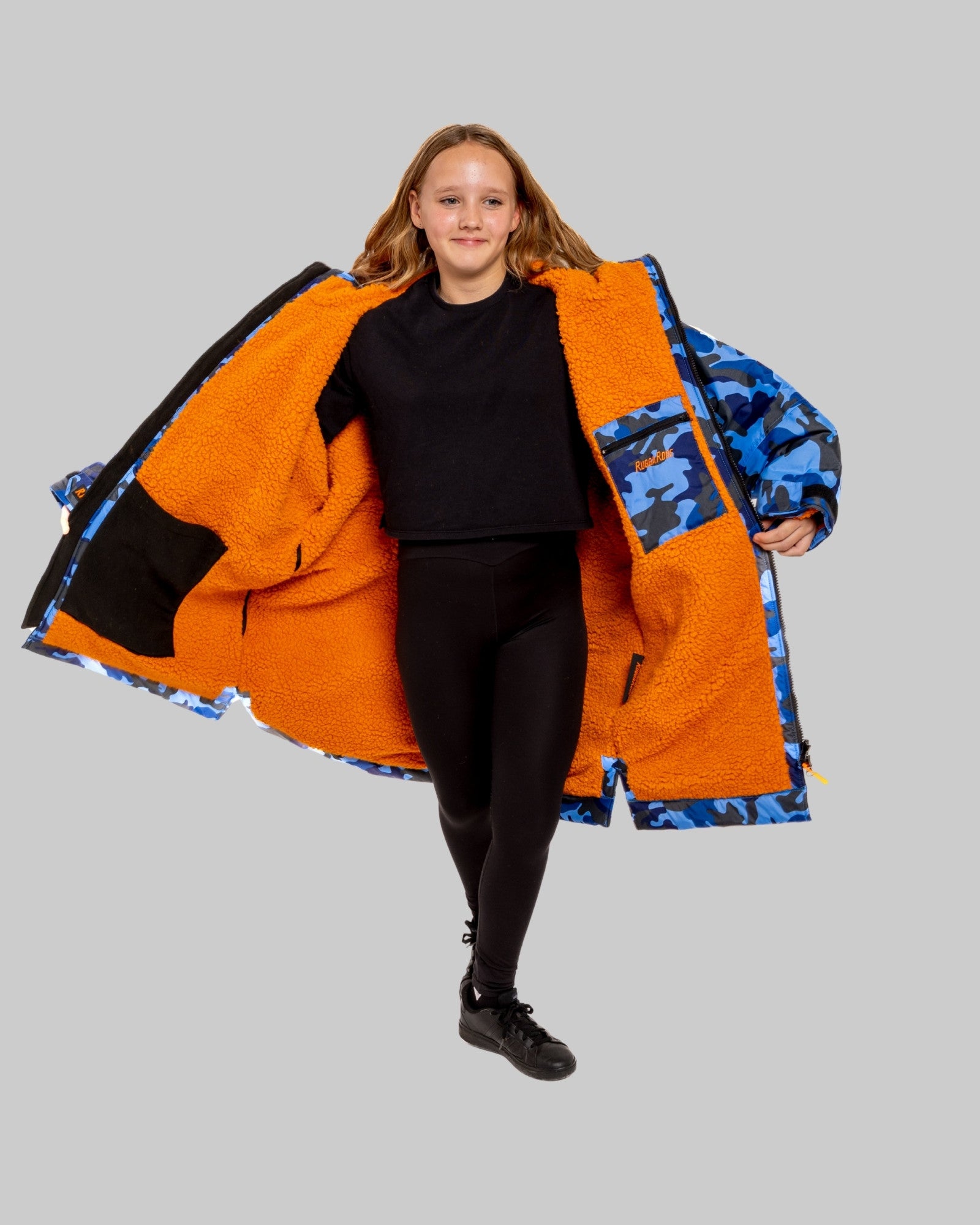 Model wearing RuggaRobe blue camo change robe with orange fleece interior on grey background