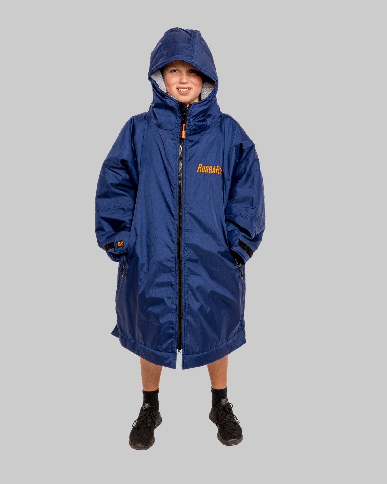 Child wearing a blue RuggaRobe with grey fleece interior change robe on a grey background