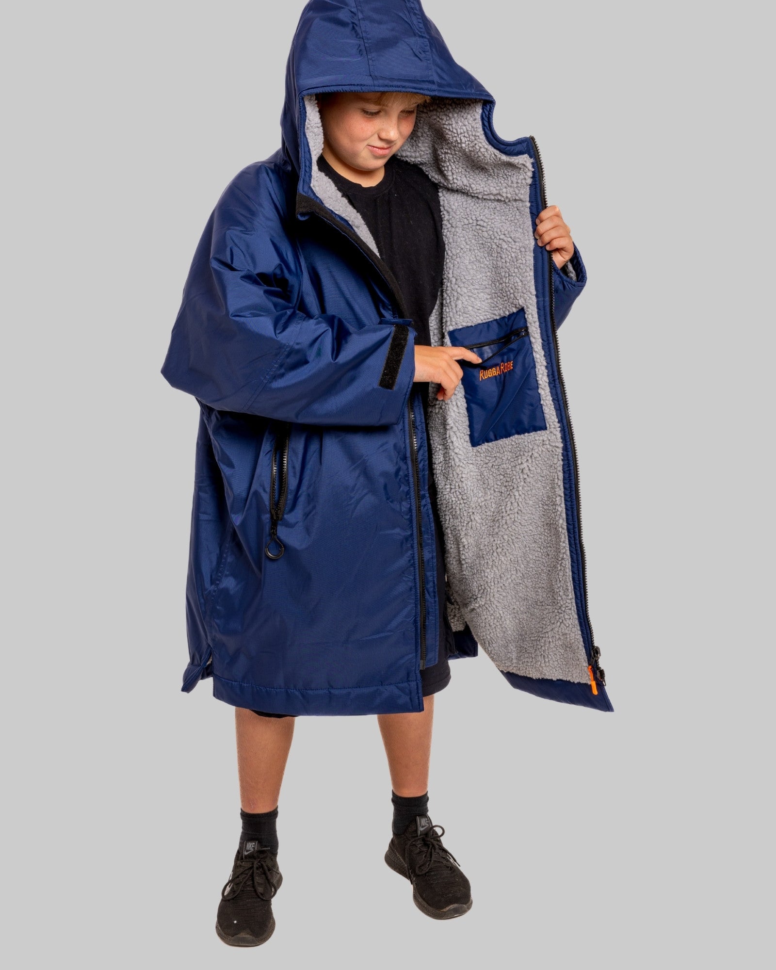 Child wearing a blue RuggaRobe with grey fleece interior change robe on a grey background