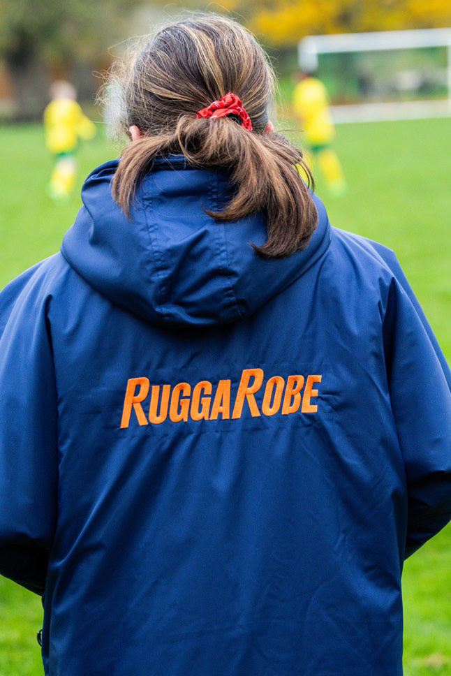 Person wearing a blue RuggaRobe change robe on a sports field