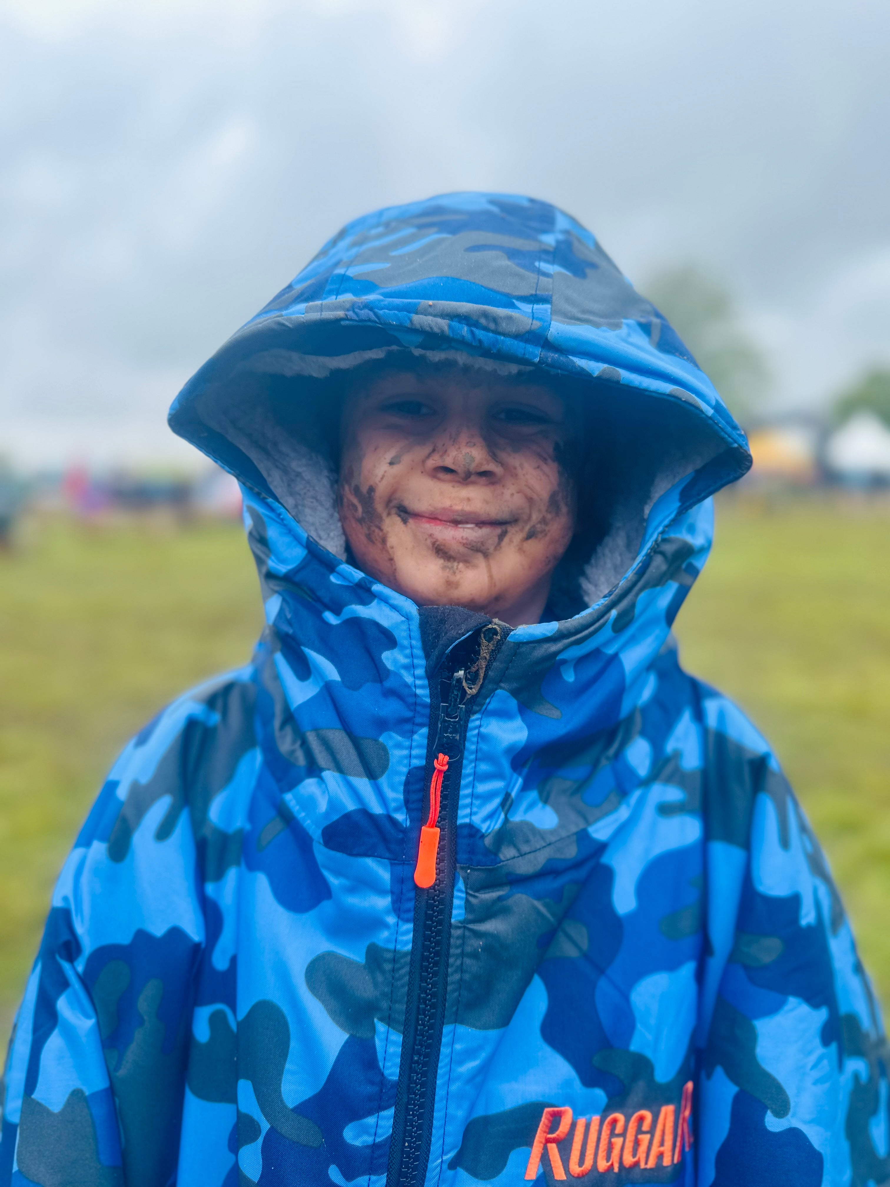 Person wearing a blue camouflage raincoat with 'Ruggarobe' branding outdoors.