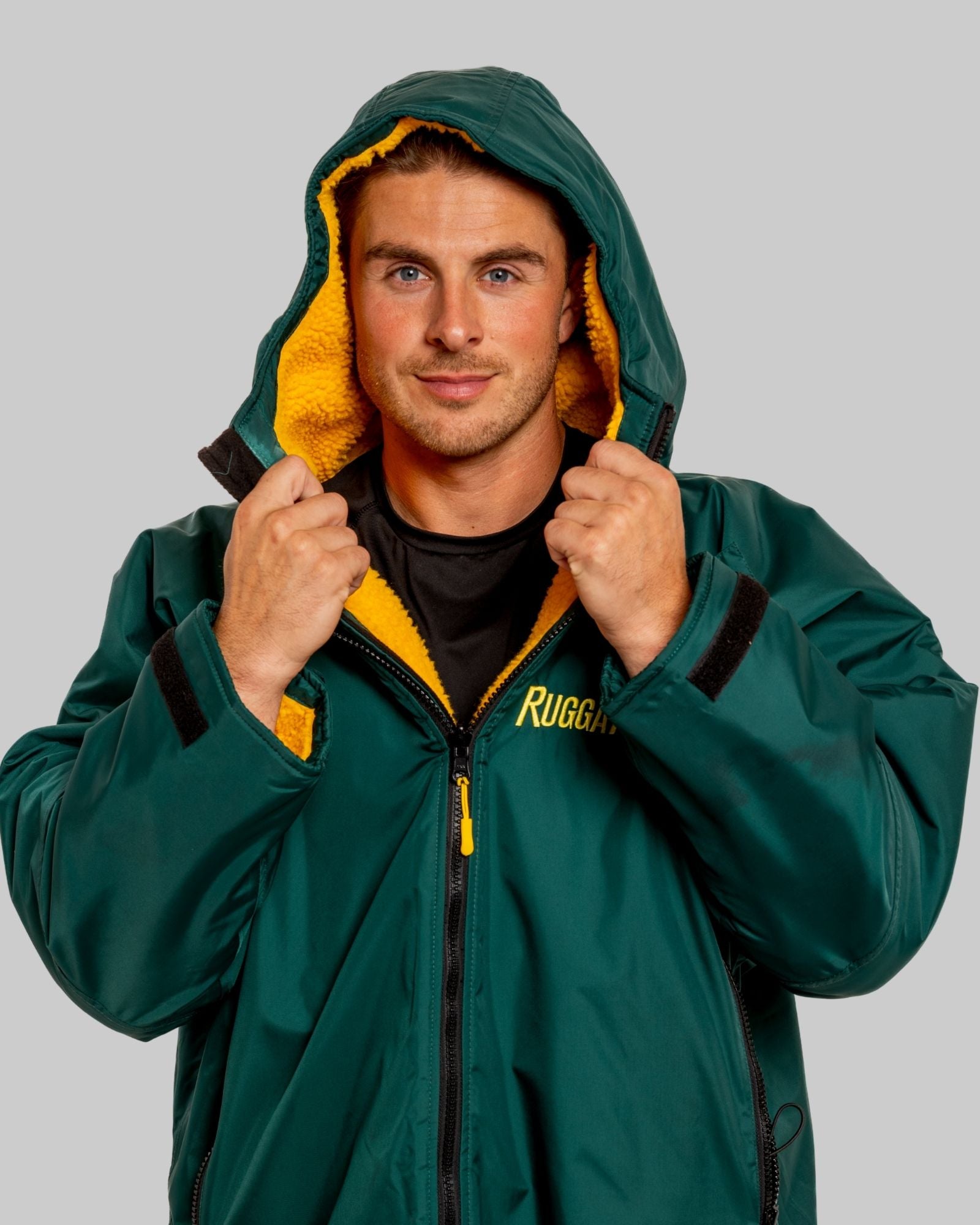 Man wearing a green jacket with yellow lining and 'Ruggarobe' branding on a grey background