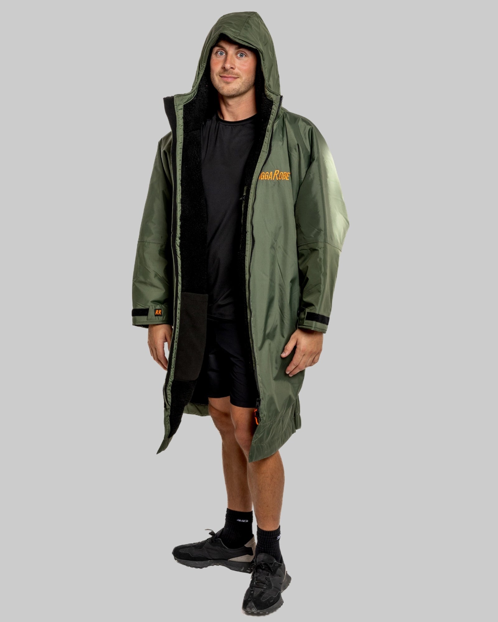 Man wearing a green change robe with black fleece with a brand logo on a grey background