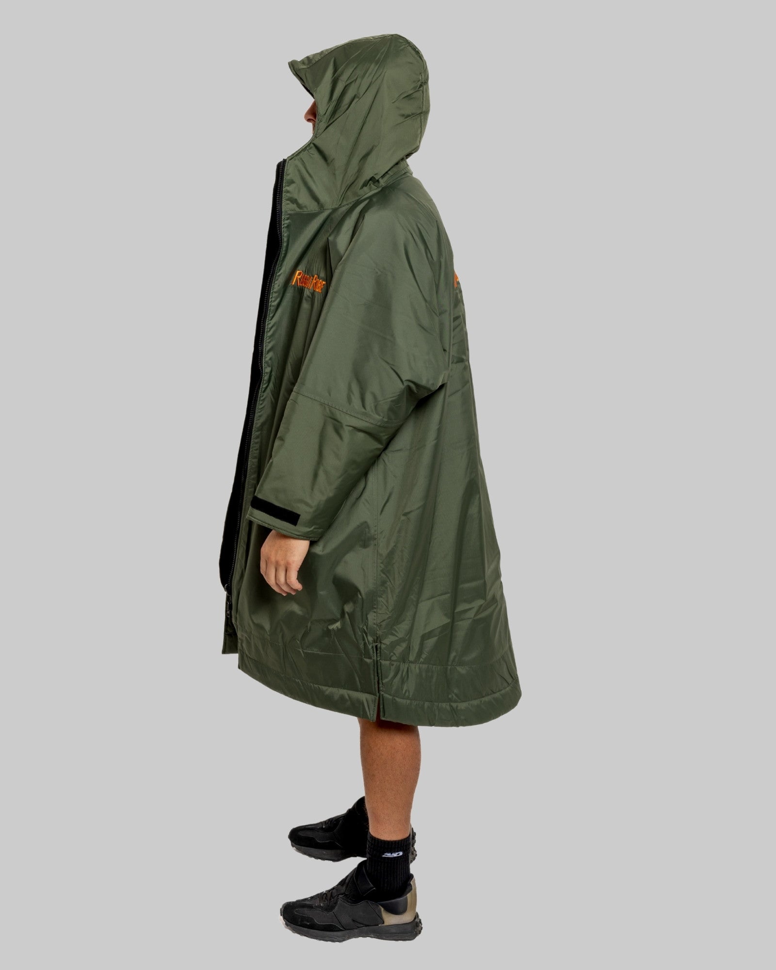 Man wearing a green change robe with black fleece with a brand logo on a grey background
