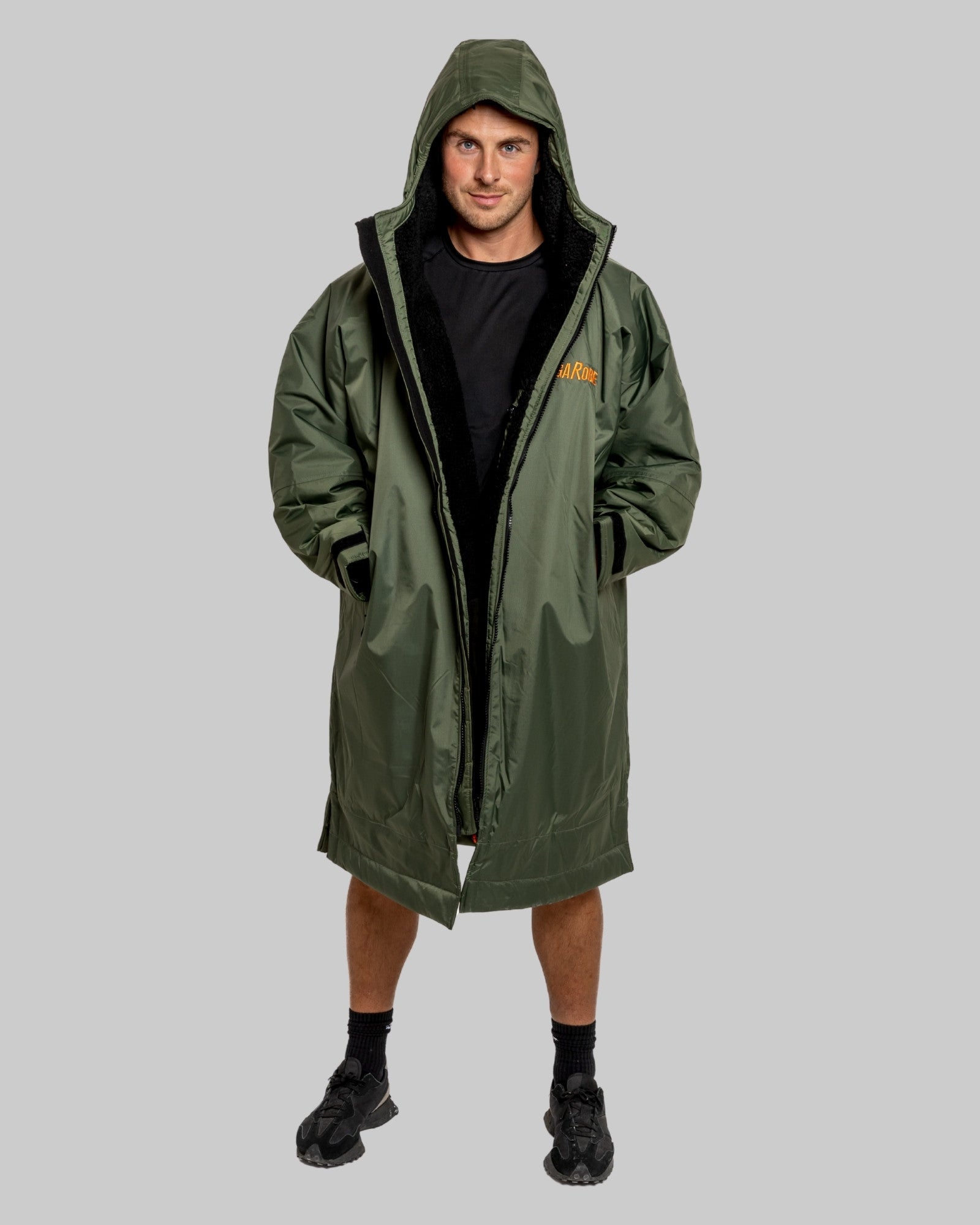 Man wearing a green change robe with black fleece with a brand logo on a grey background