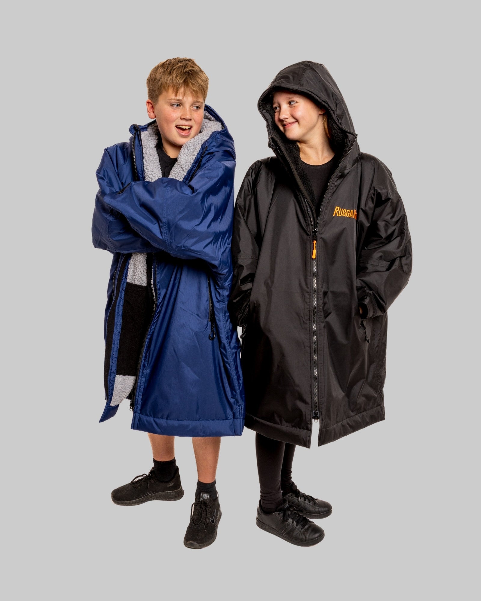2 Children wearing RugaRobe change robes, one blue robe and one black robe on a grey background