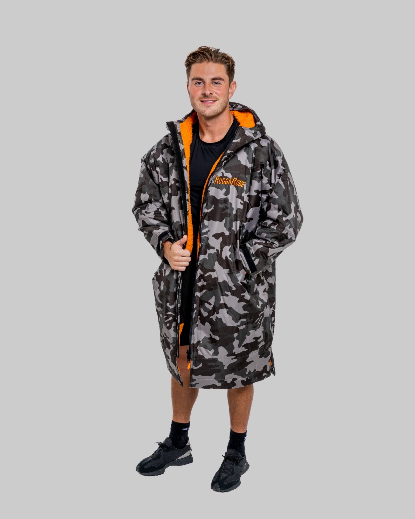 Model wearing RuggaRobe grey camo change robe with orange fleece interior on grey background