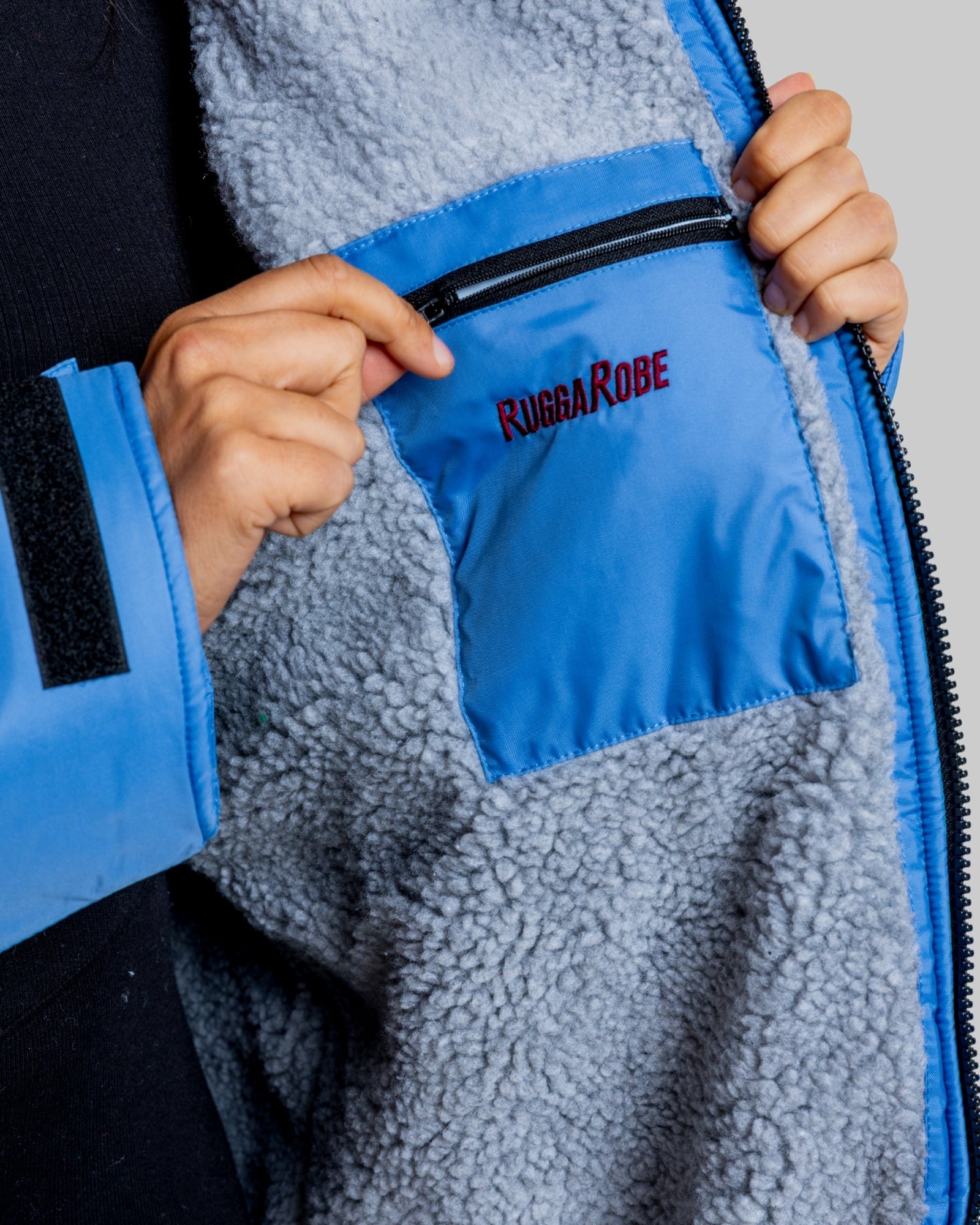 Close-up of a blue and gray fleece jacket with 'RuggaRobe' branding.