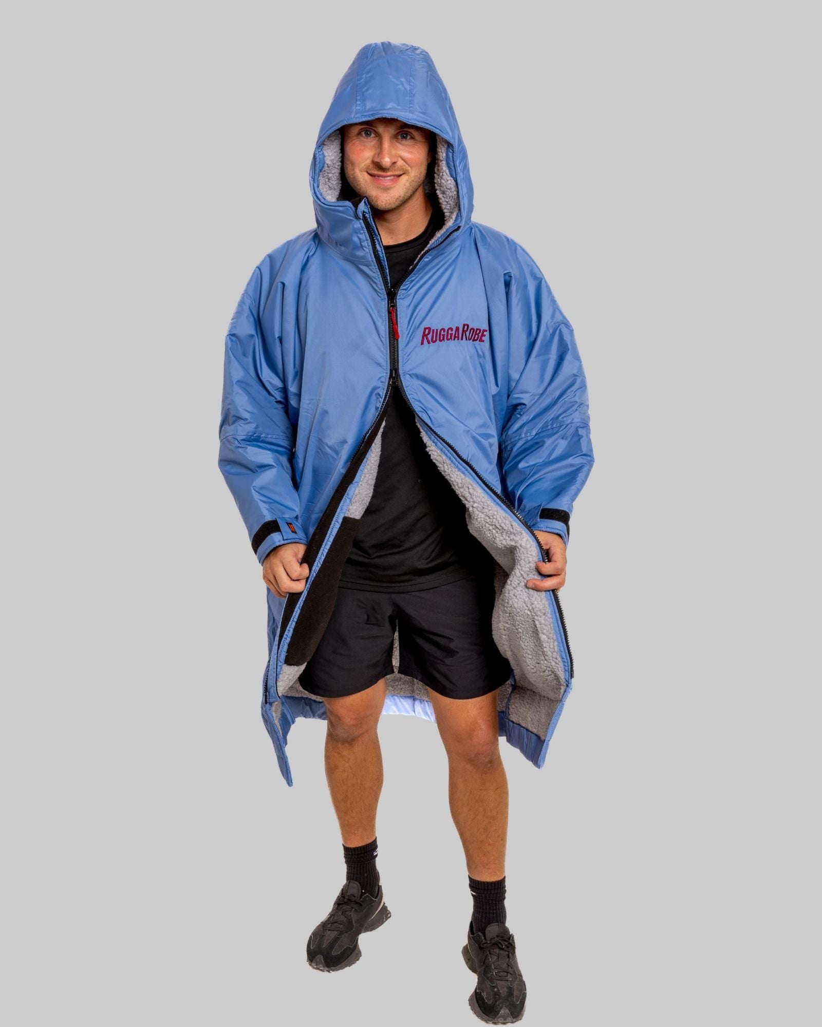 Person wearing a blue hooded jacket with a visible brand logo on a gray background