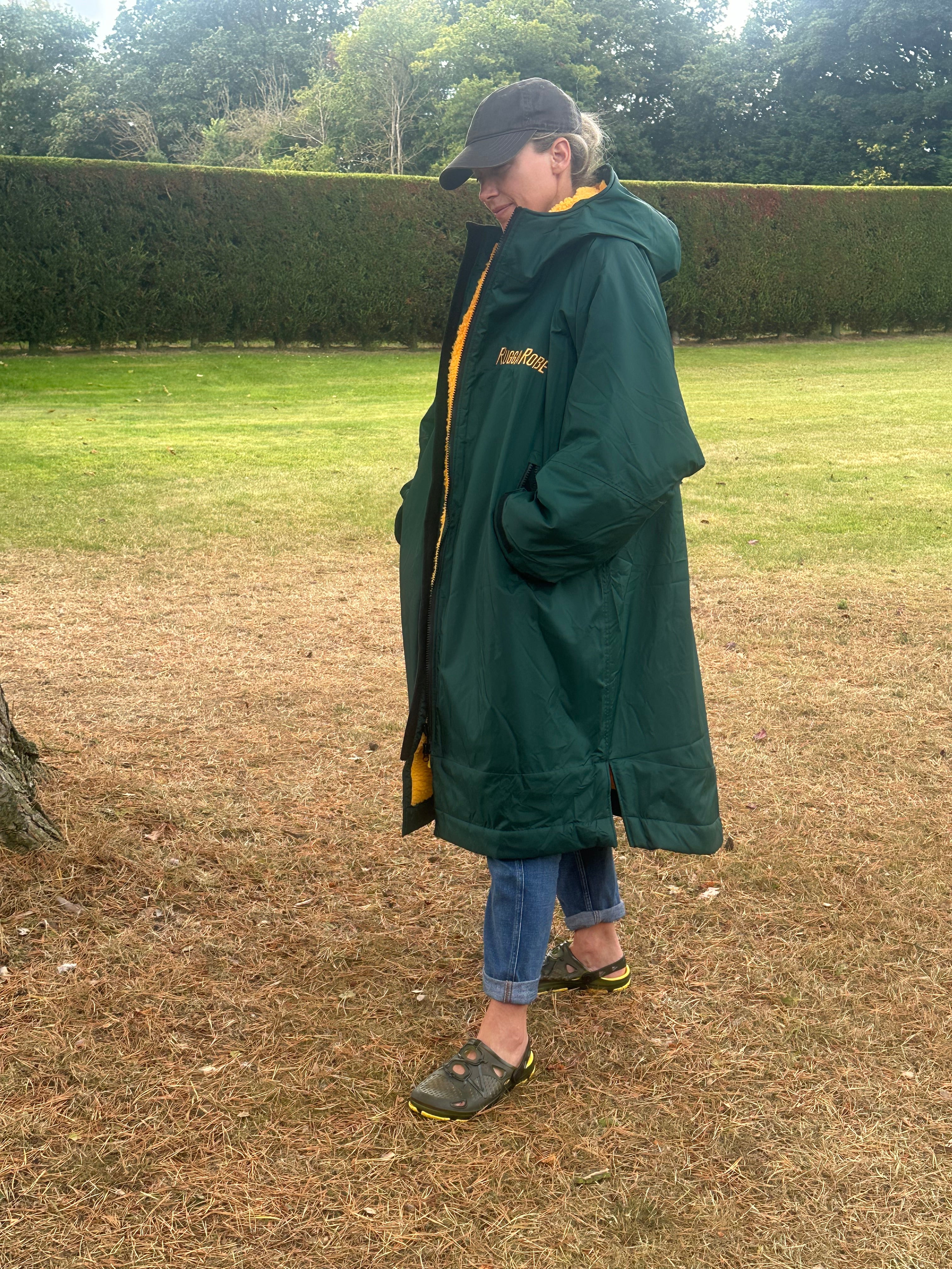 Person wearing a green with gold fleece change robe in a field
