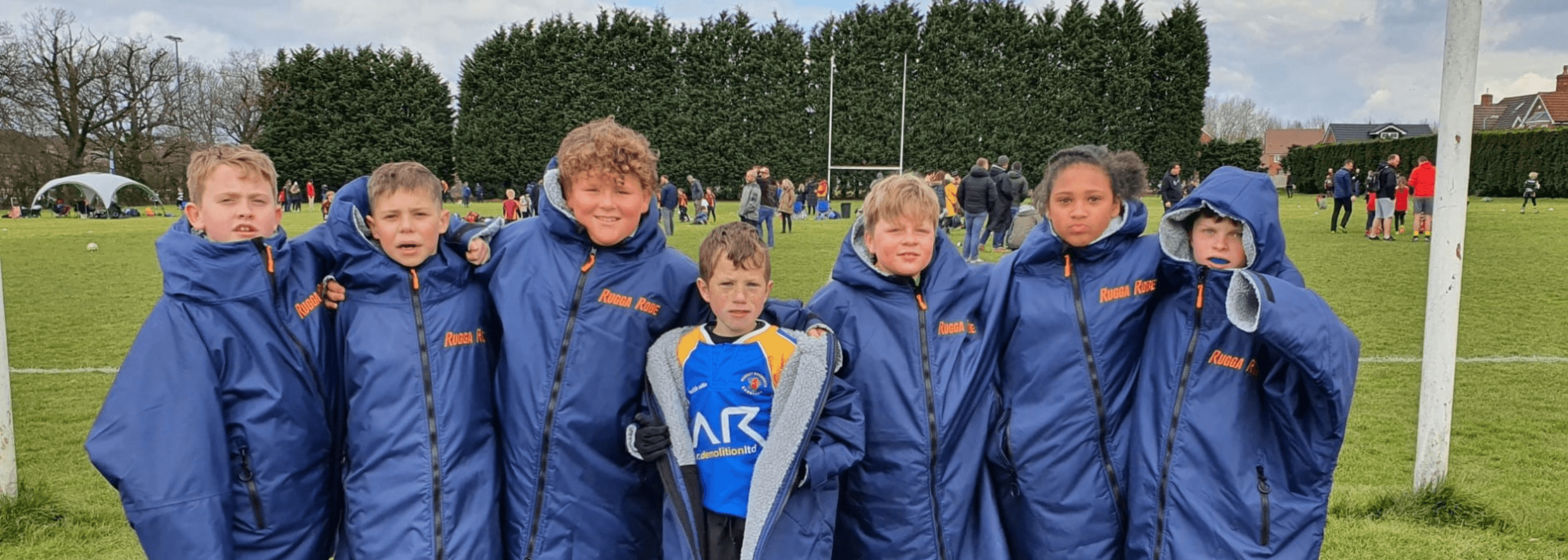 Group of young rugby players wearing blue ruggarobes on rugby pitch