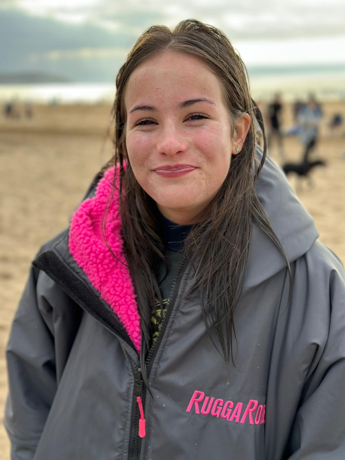 Person wearing a gray changerobe with pink lining and 'Rugga Robe' branding in an outdoor setting.