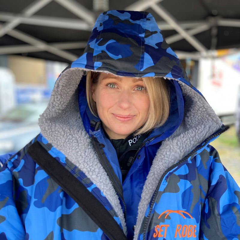 Model wearing a blue cam with grey fleece interior in a tv film set