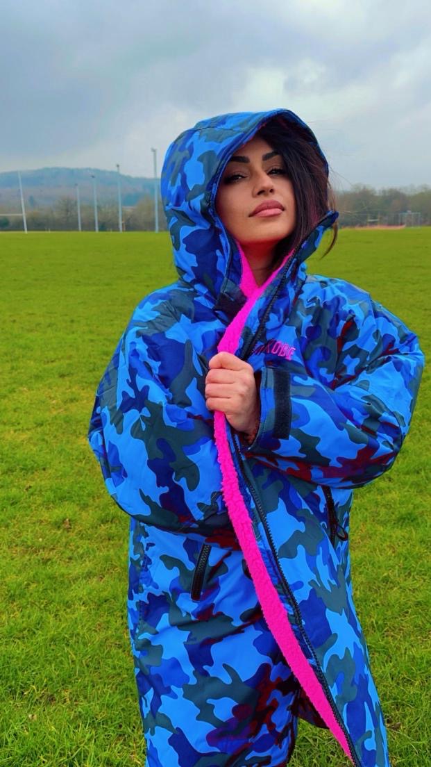 Model wearing RuggaRobe blue camo change robe with grey fleece interioron a sportsfield