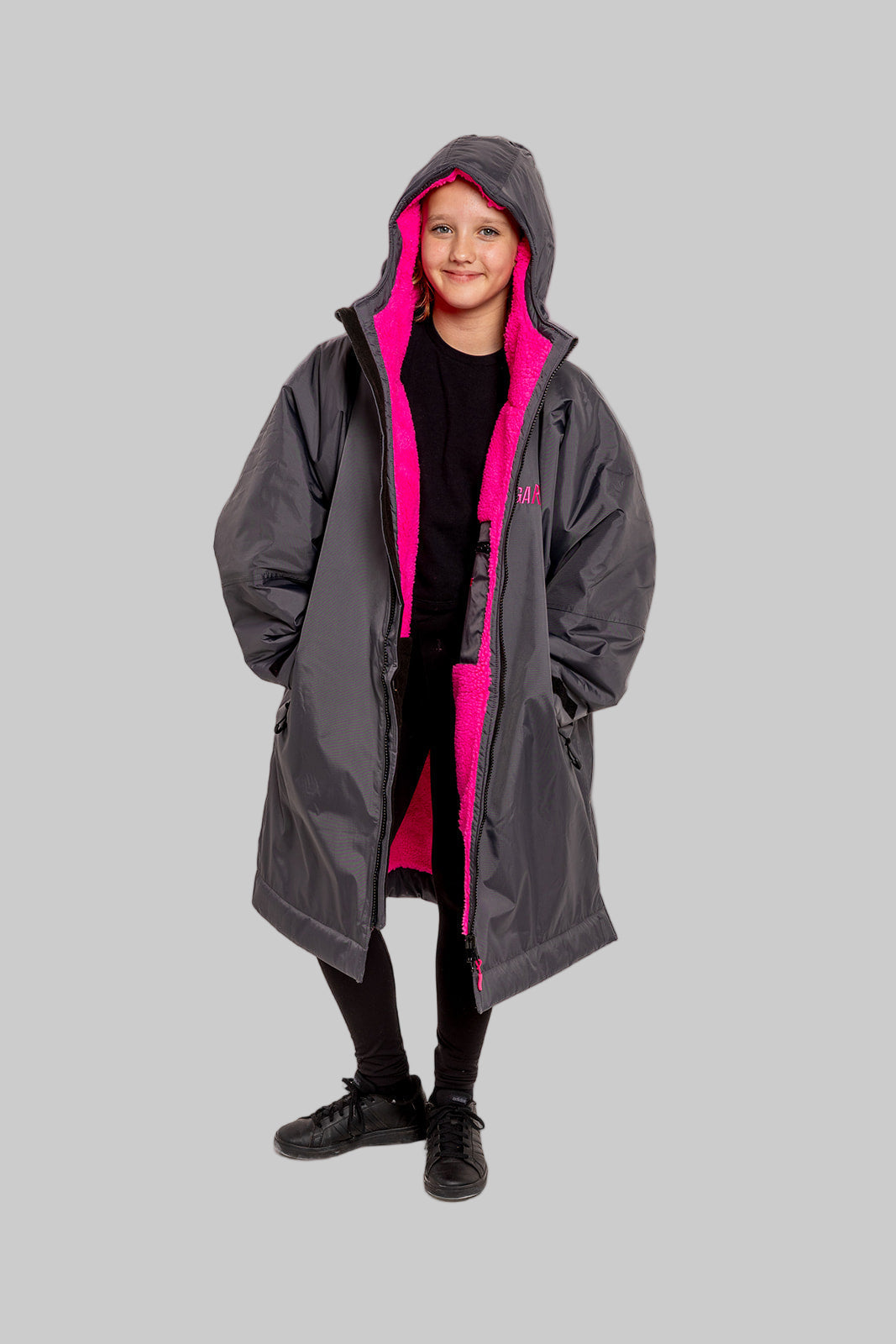 Model wearing RuggaRobe slate grey change robe with pink fleece interior on grey background